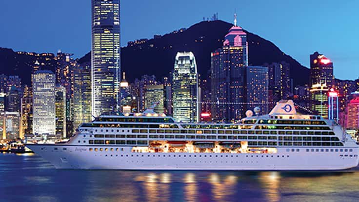 Oceania cruise ship docked in Victoria Harbor with Hong Kong skyline at twilight
