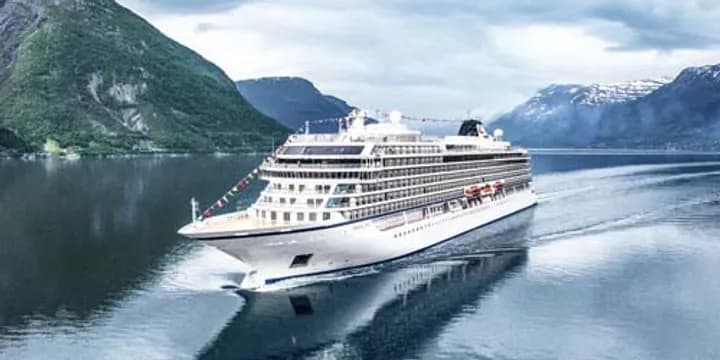 Luxury Cruise Ship in Norwegian Fjord A pristine white cruise ship anchored in a serene Norwegian fjord, surrounded by dramatic