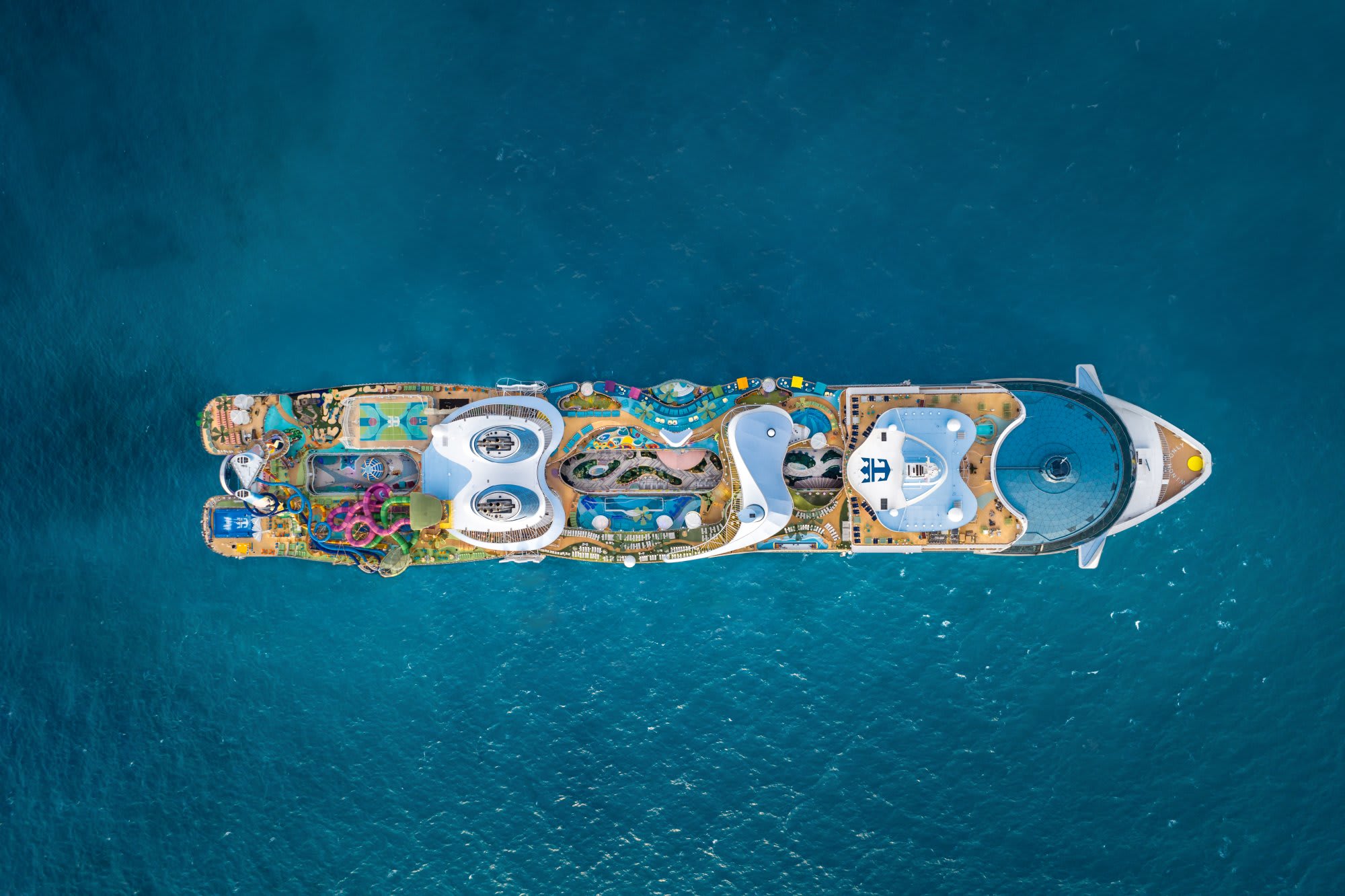 An overhead aerial view of a large modern cruise ship anchored in turquoise Caribbean waters
