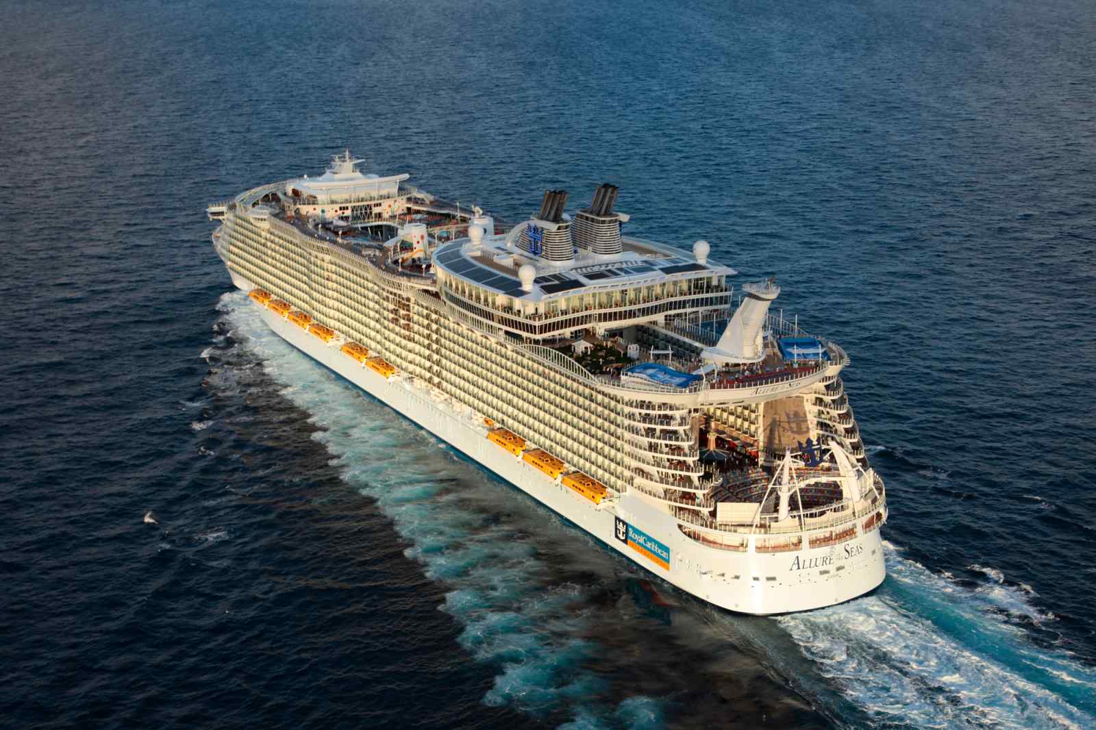 An aerial view of the Allure of the Seas, a massive modern cruise ship, positioned in shallow