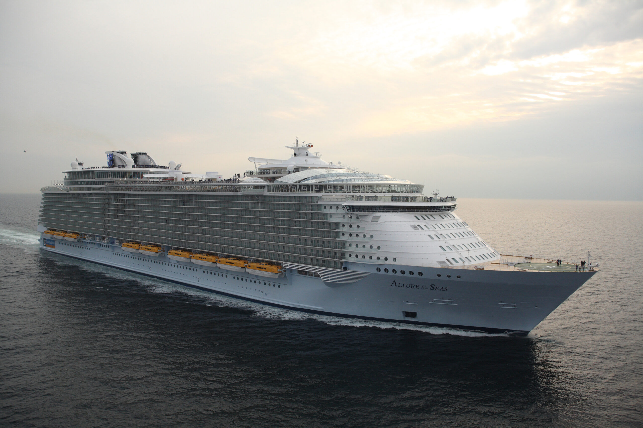A massive Royal Caribbean cruise ship sailing on open waters during a soft, overcast day