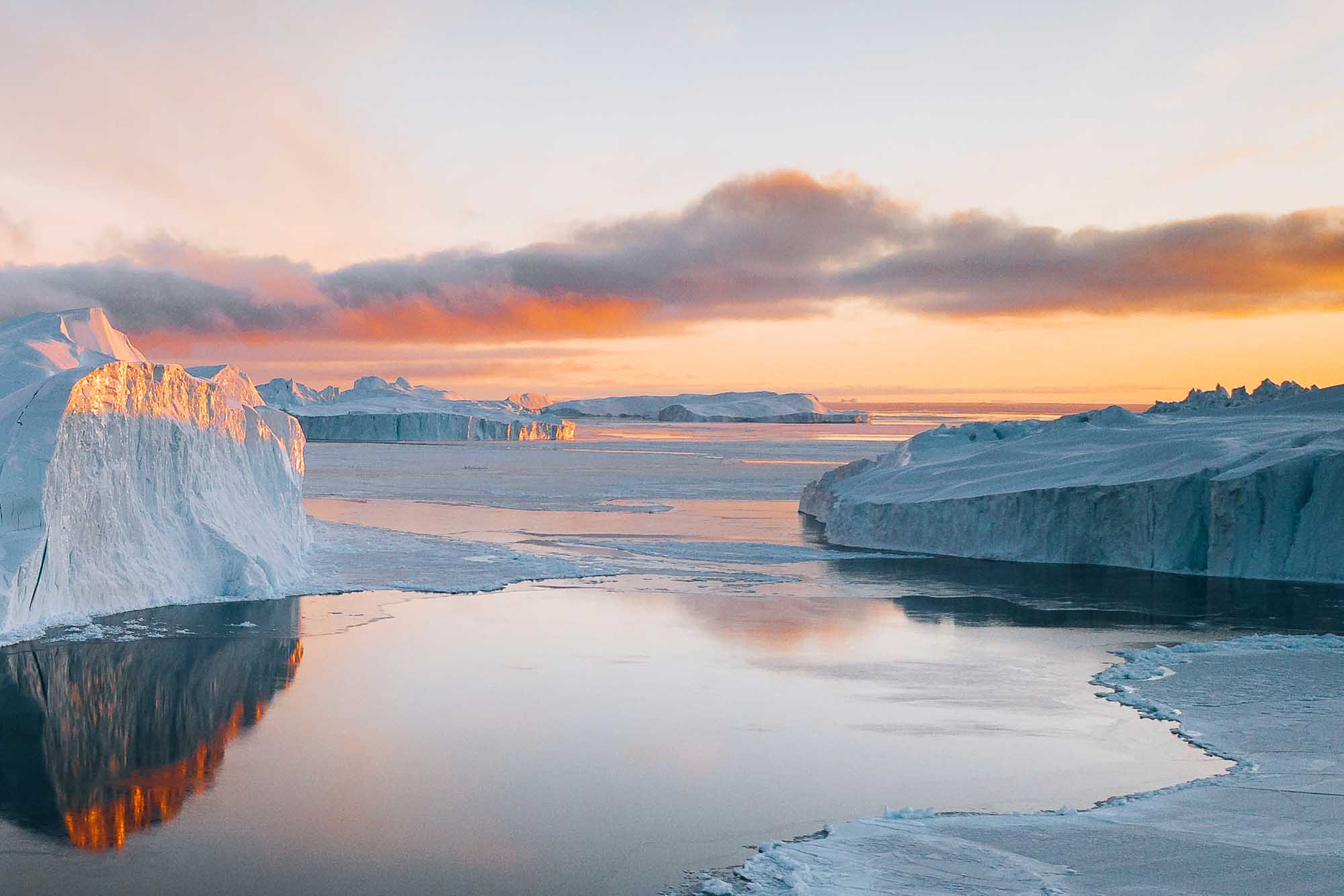 A stunning arctic landscape featuring massive icebergs with white and blue hues reflected in
