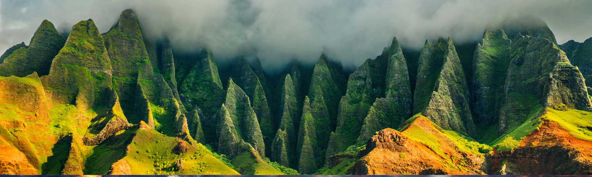 The iconic Na Pali Coast features towering emerald-green fluted cliffs rising dramatically from