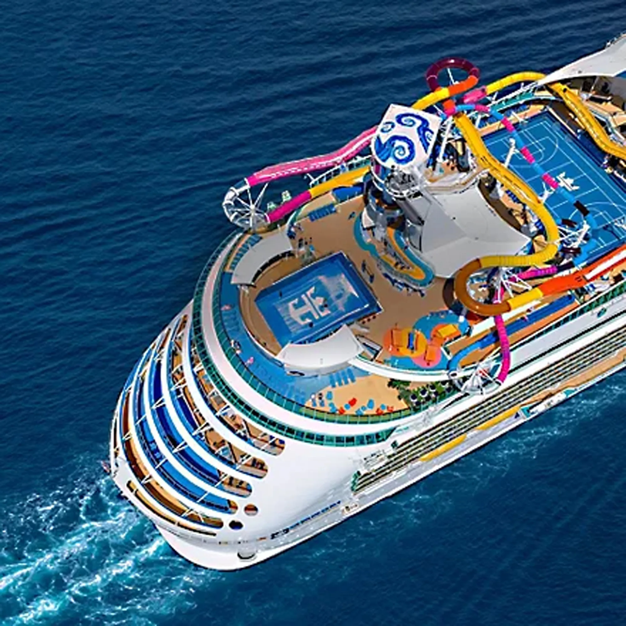 An aerial view of a large cruise ship featuring colorful waterslides, multiple deck levels