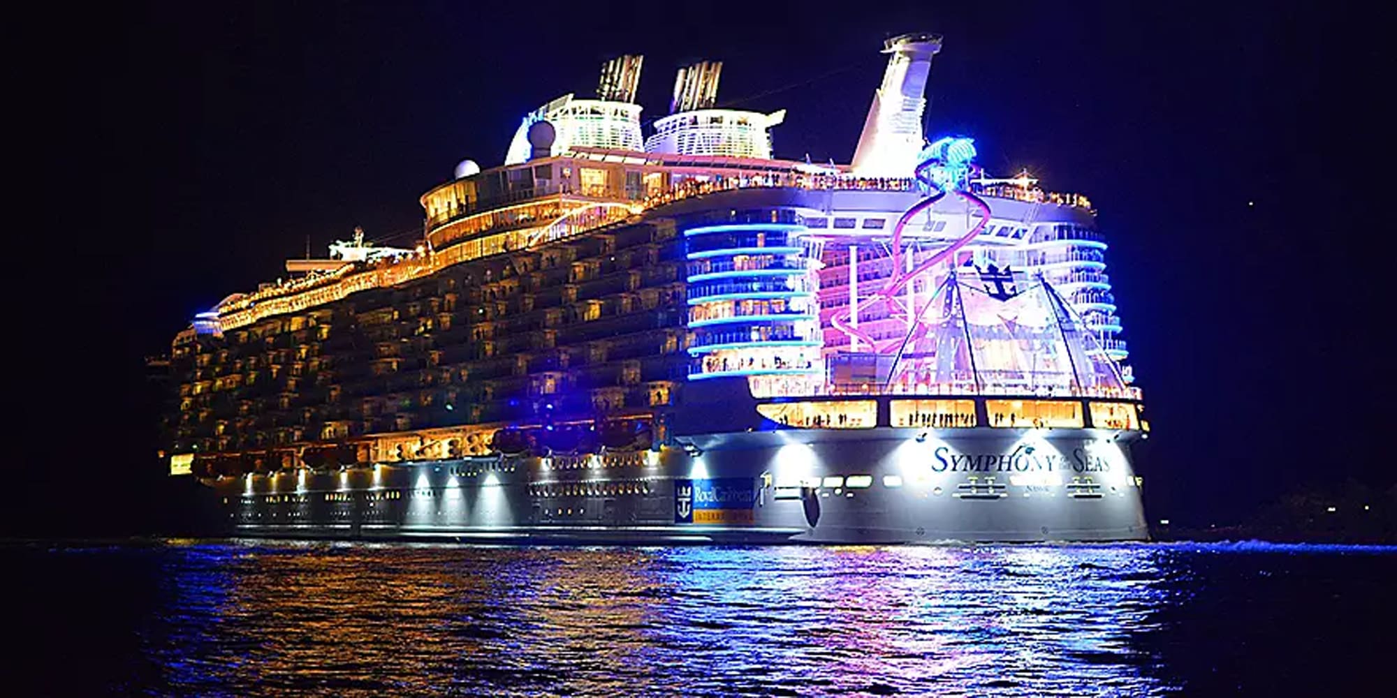 A magnificent cruise ship brilliantly lit up at night on dark ocean waters, displaying spectacular