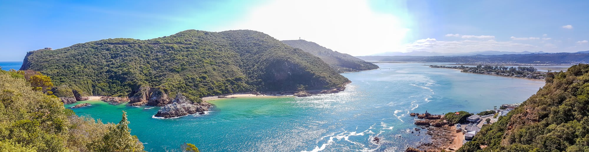 A stunning panoramic view of a pristine tropical coastline featuring a verdant, densely forested
