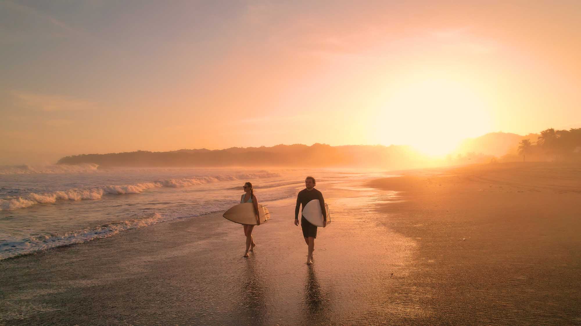 Aerial:,Cheerful,Surfers,Admire,Big,Waves,While,Walking,On,Sandy shutterstock-2316960939.jpg