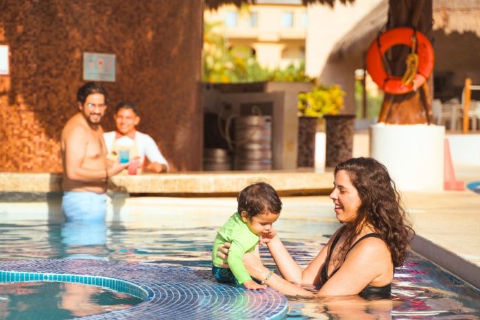 Familia disfrutando piscina y alberca en All Ritmo Cancún Resort con toboganes acuáticos