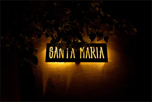Vista nocturna de la fachada de la Villa Santa María, con iluminación cálida y ambiente acogedor.