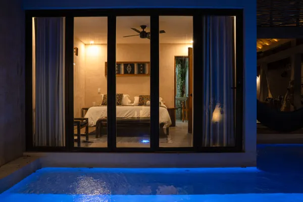 Vista principal de la alberca de la Villa Noyollo, iluminada de noche.