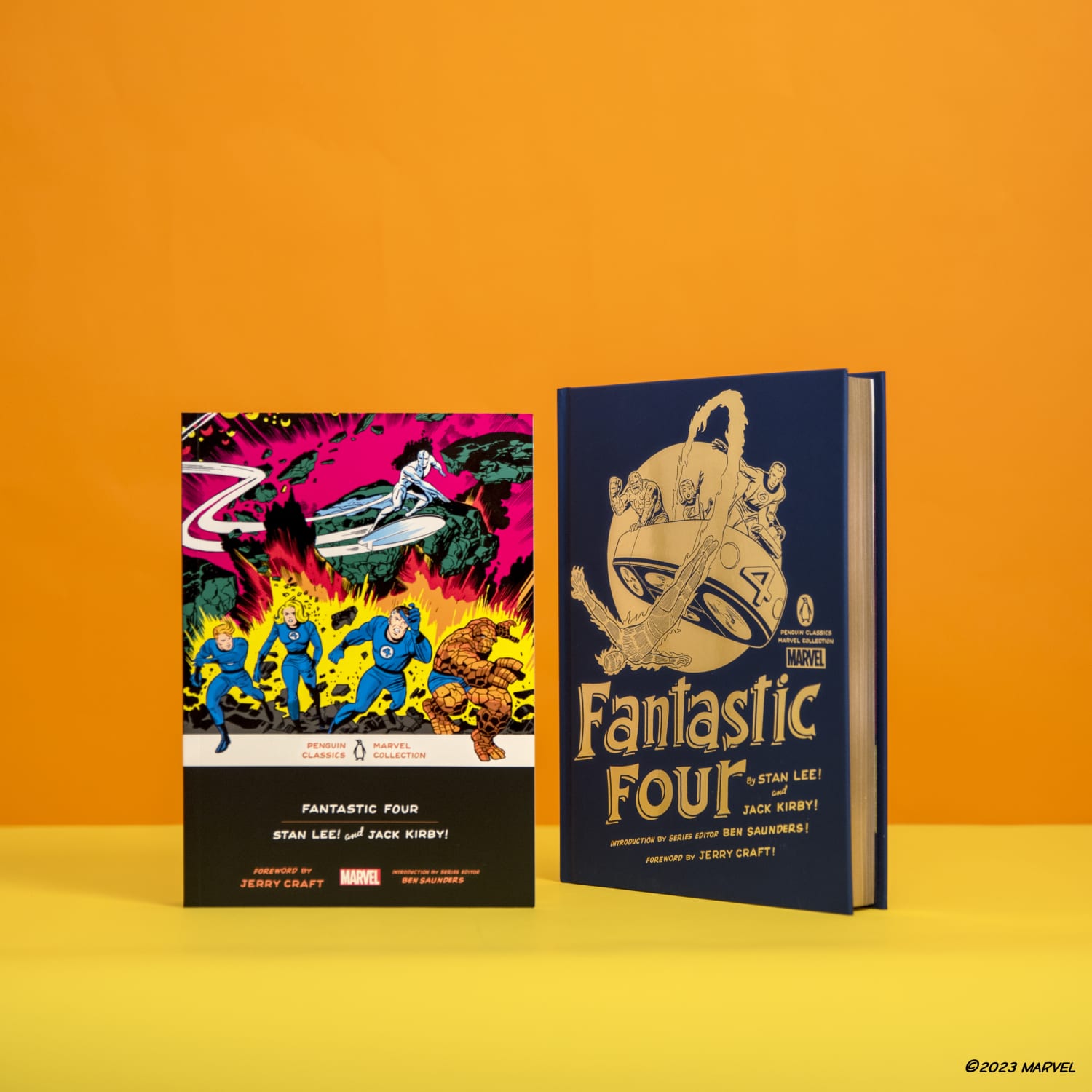 Fantastic Four hardcover and paperback editions standing against orange background