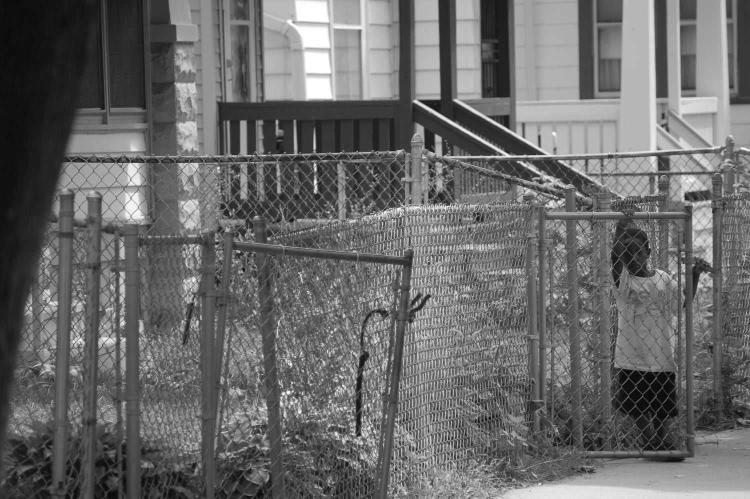 A Black child standing behind a chain link fence