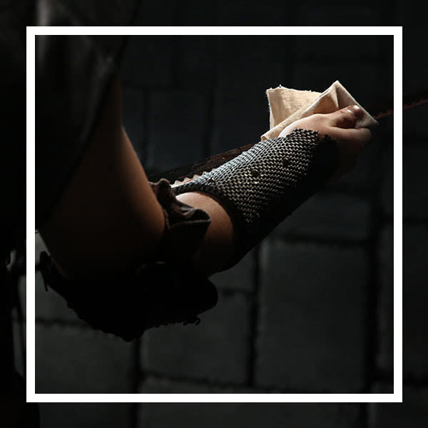 A person&#039;s arm wearing armor, holding a rag