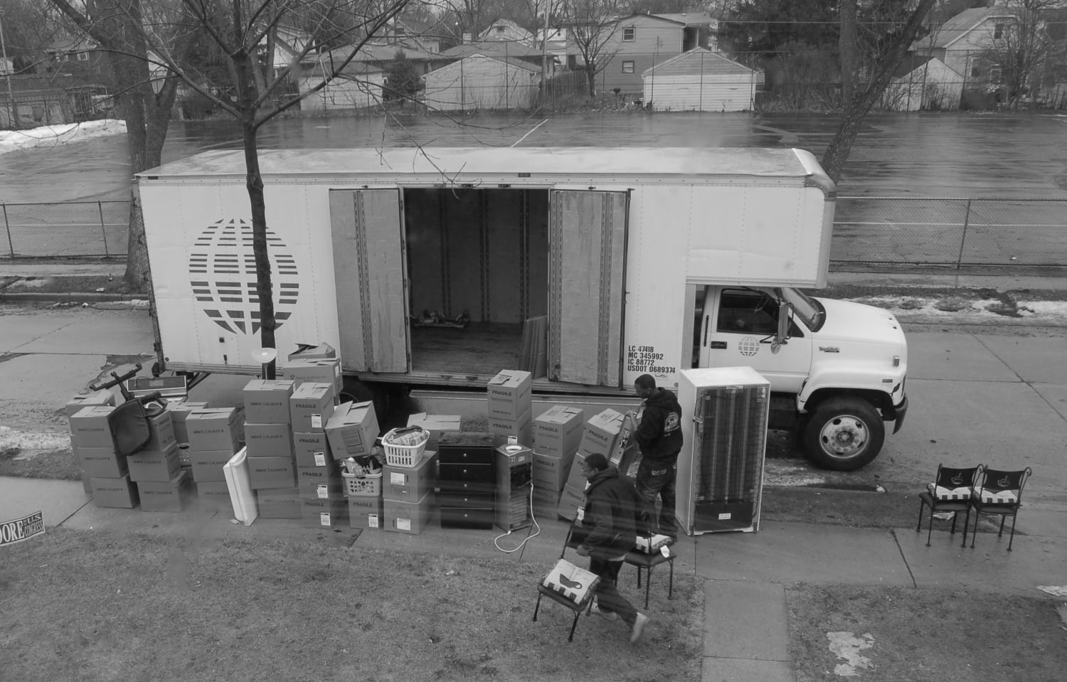 Movers loading a truck with boxes, furniture, and a refrigerator