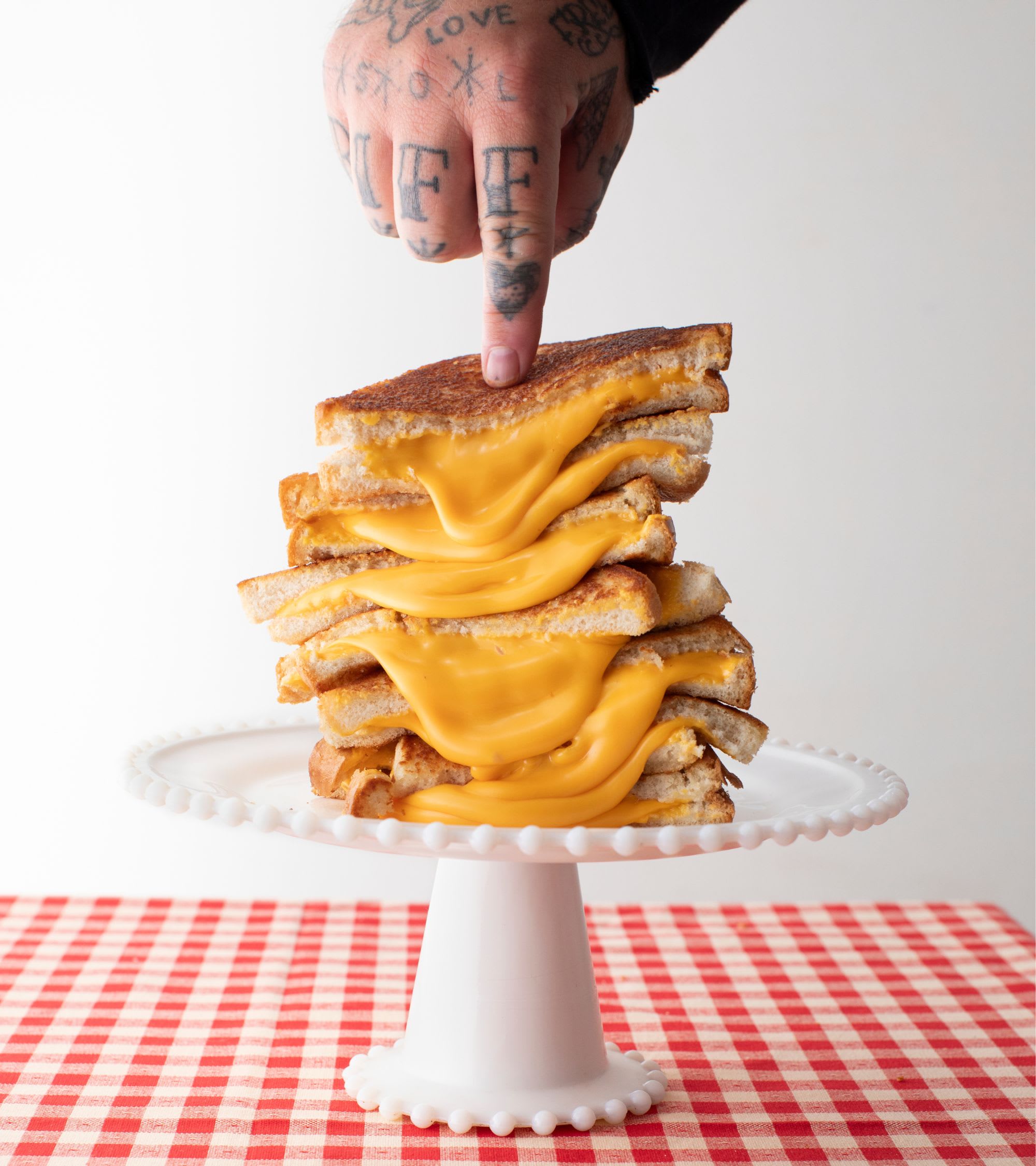 Matty using pointer finger to push down on stack of grilled cheese