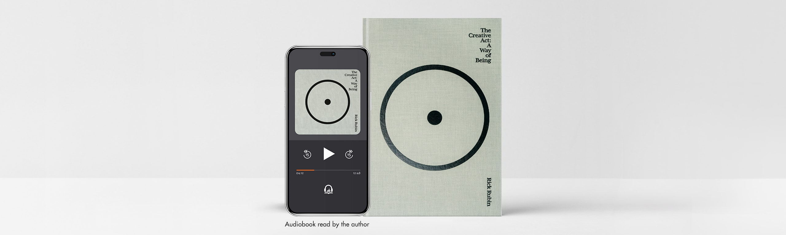 A copy of The Creative Act stands against a gray background with a phone propped to the left of it with the audiobook on the screen. A line of text underneath the phone says “Audiobook read by the author.”