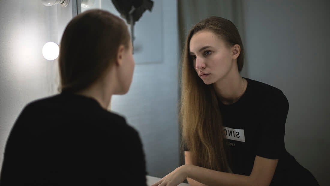 Woman looking at her reflection in the mirror