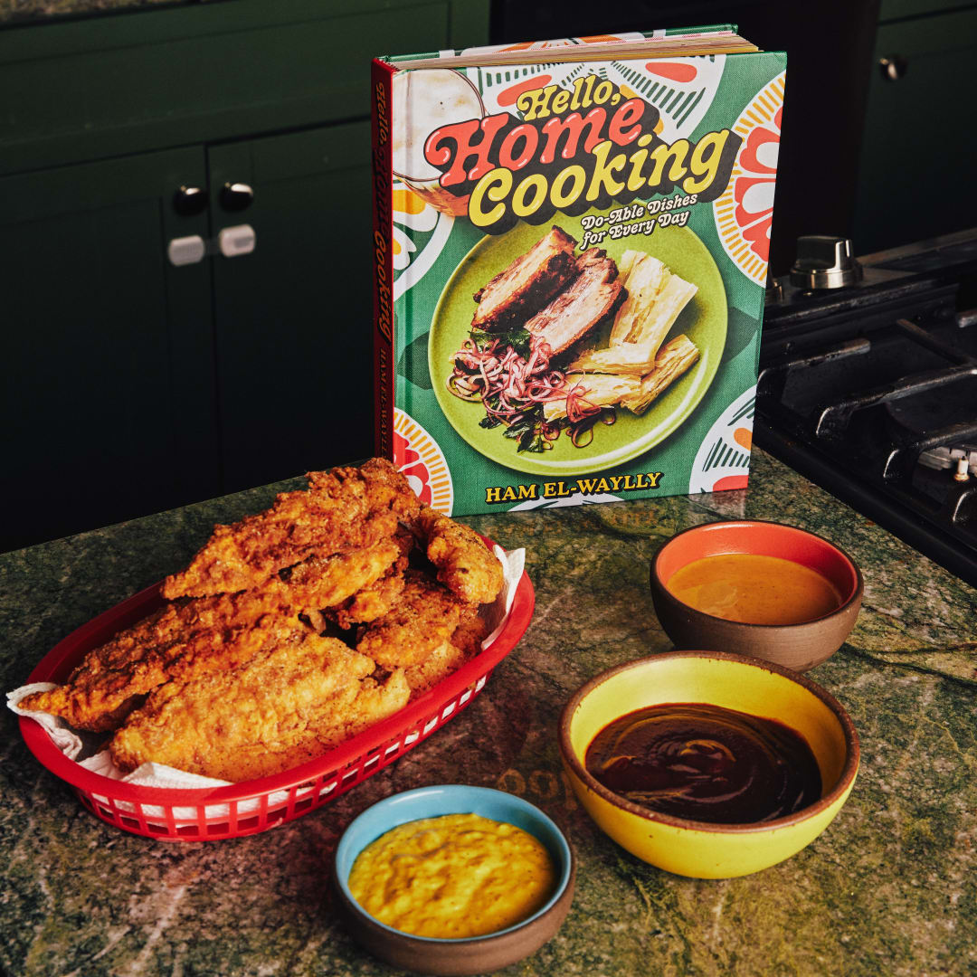 Hello Home Cooking on a kitchen countertop with homemade crispy chicken tenders in a red basket surrounded by three dipping sauces