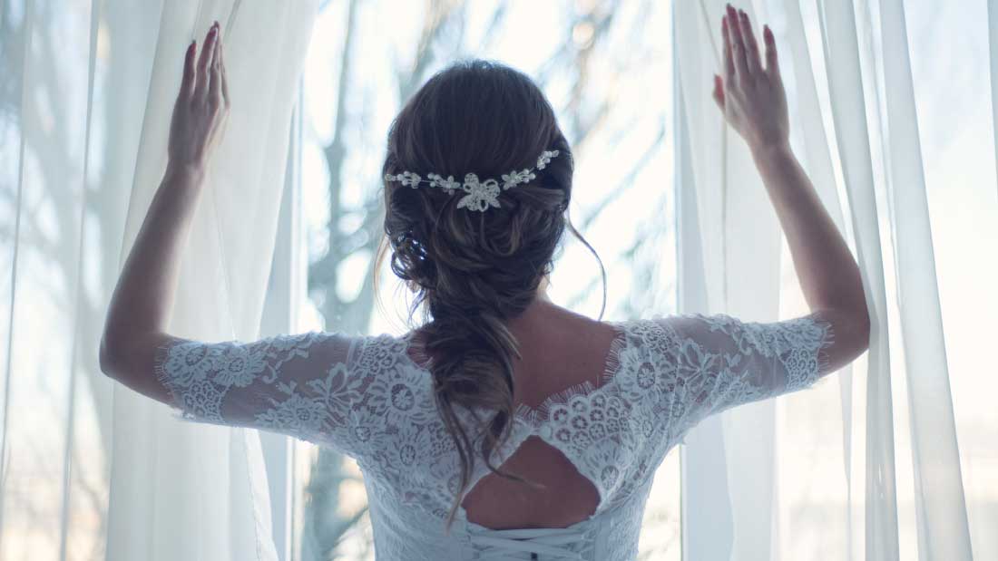 Woman in wedding dress looking out a window