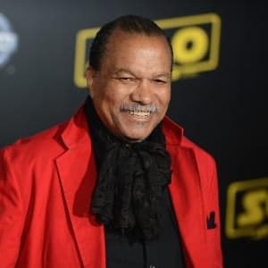 Billy Dee Williams wearing a black scarf and red coat