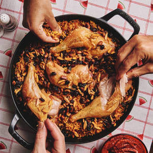 Chicken thighs atop yellow Rice served in a cast-iron skillet.