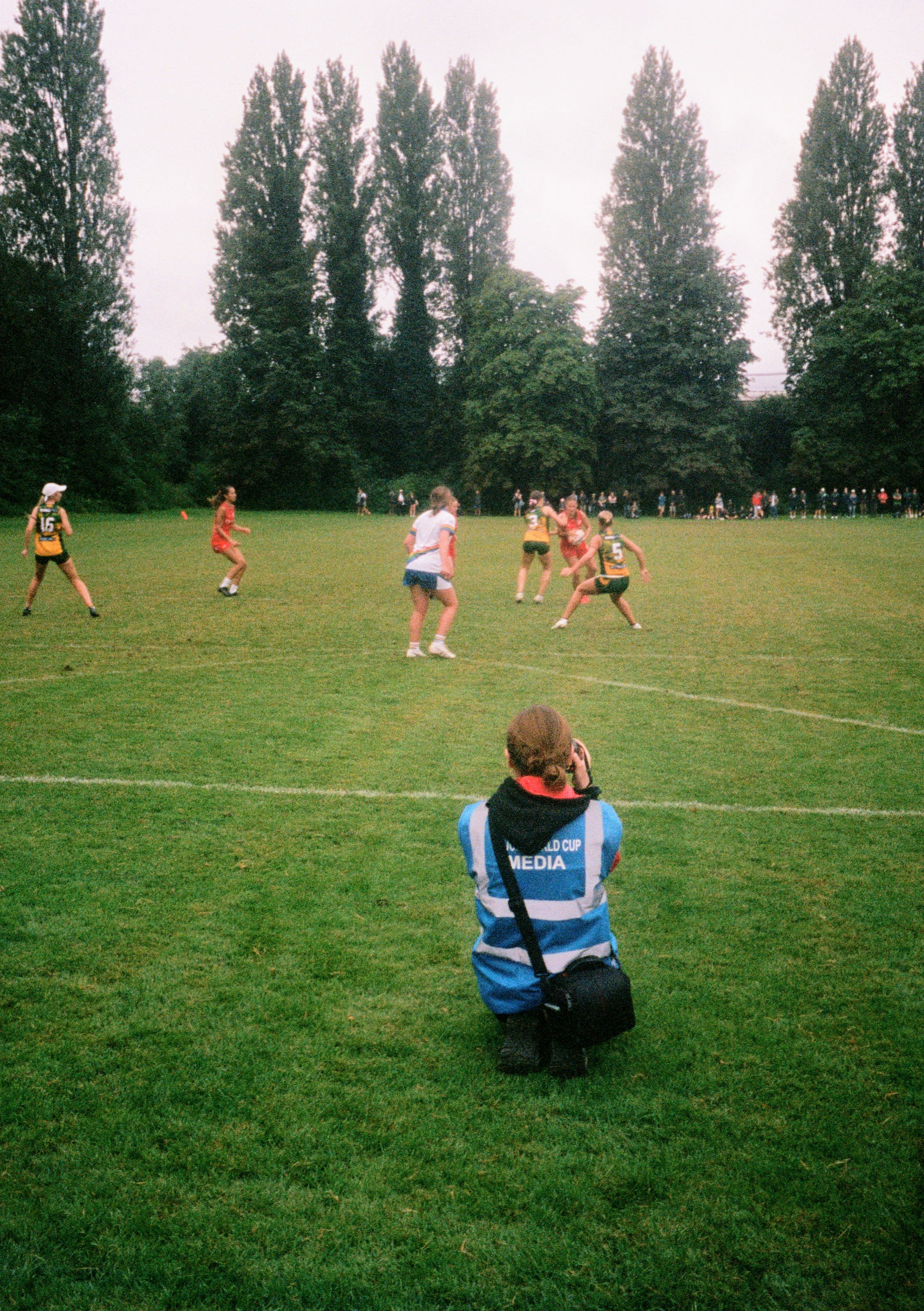 An Australian player wearing a yellow vest leans in to make a touch on a USA player wearing a red vest.