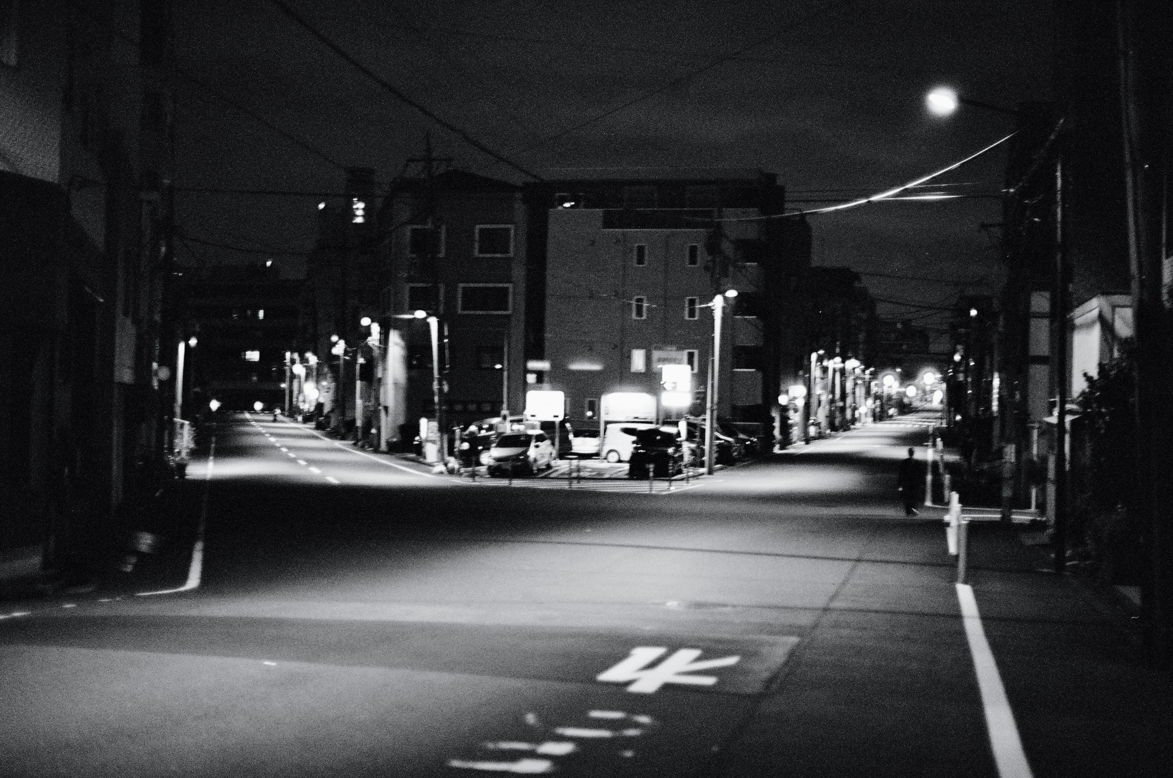 A road forks through a residential neighbourhood. Street lights illuminate the fork in the road.