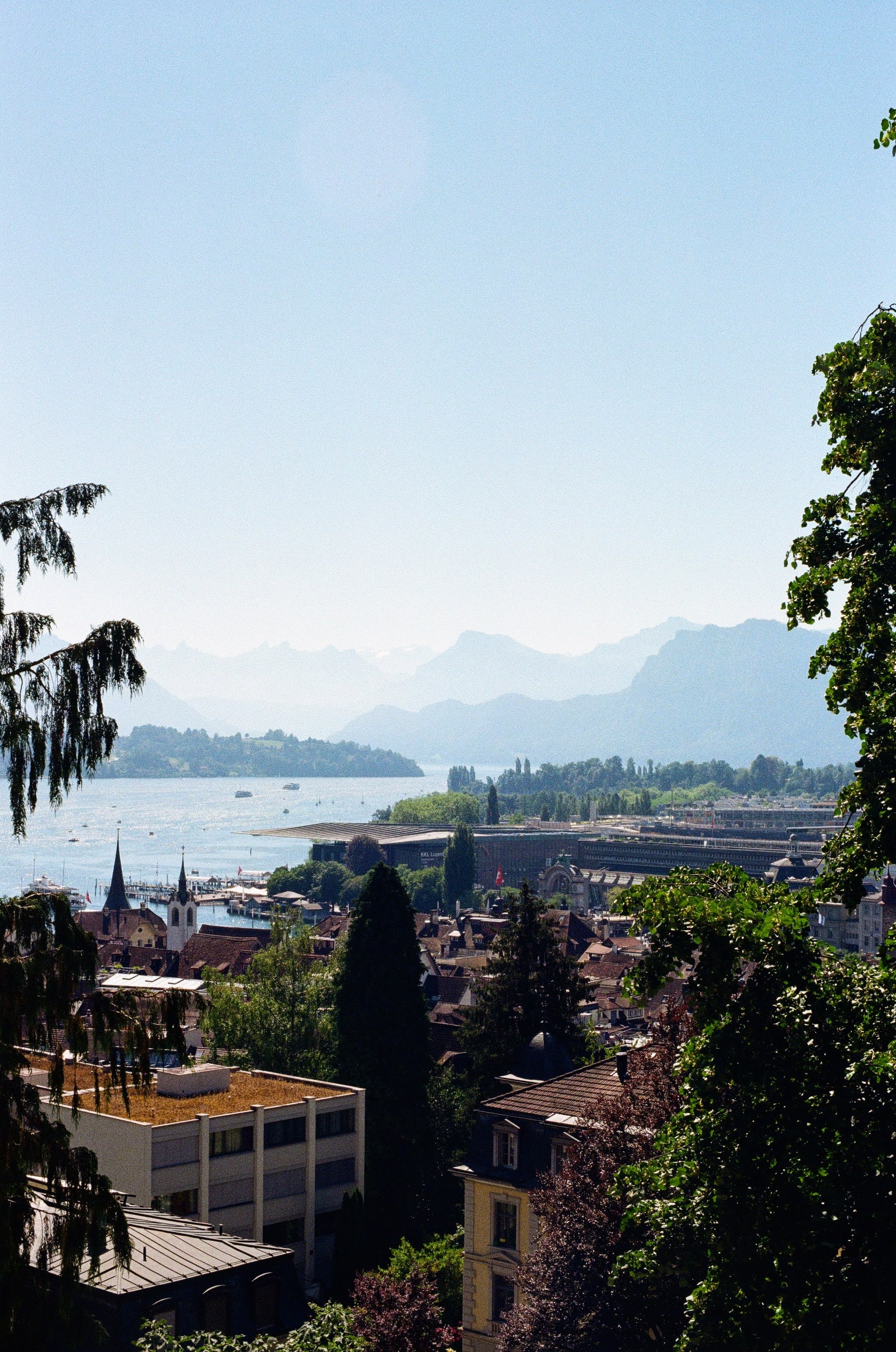 Roofs of the old town of Lucerne, next to a lake. Mountains are in the background.