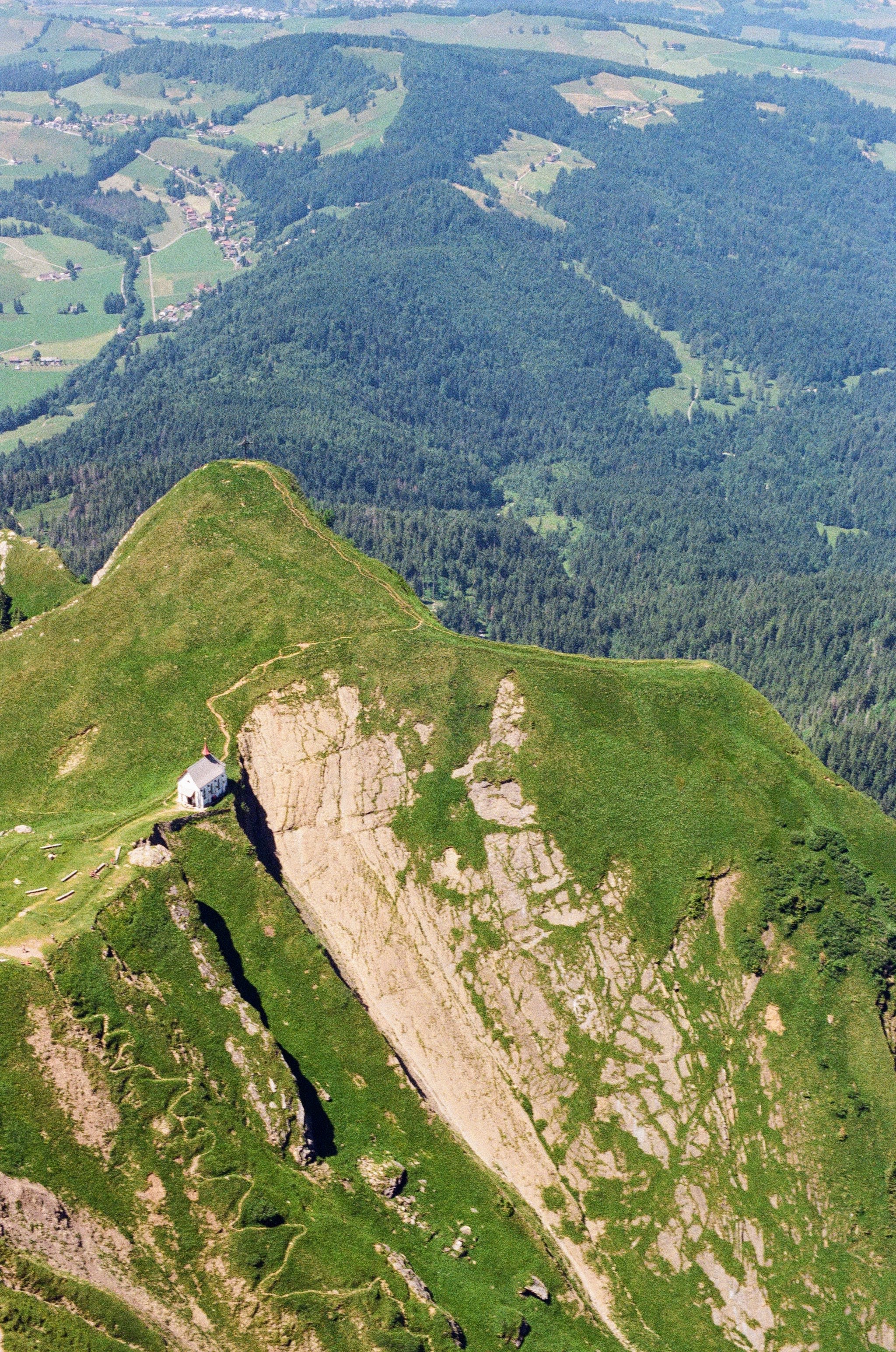 A white church sits on the ridge of a grassy incline.