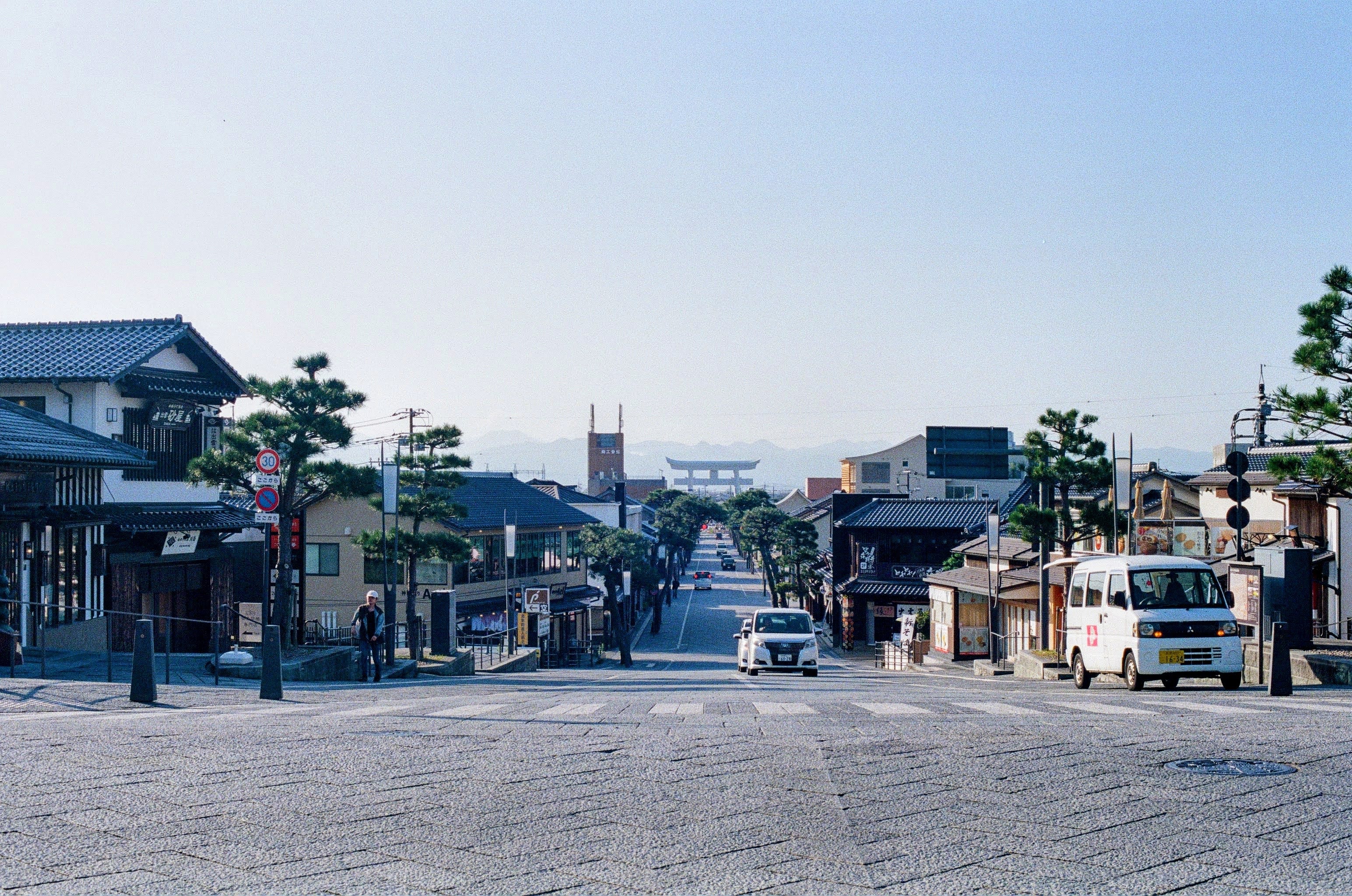 The view down a store-lined road towards a large torii gate overlooking the town.
