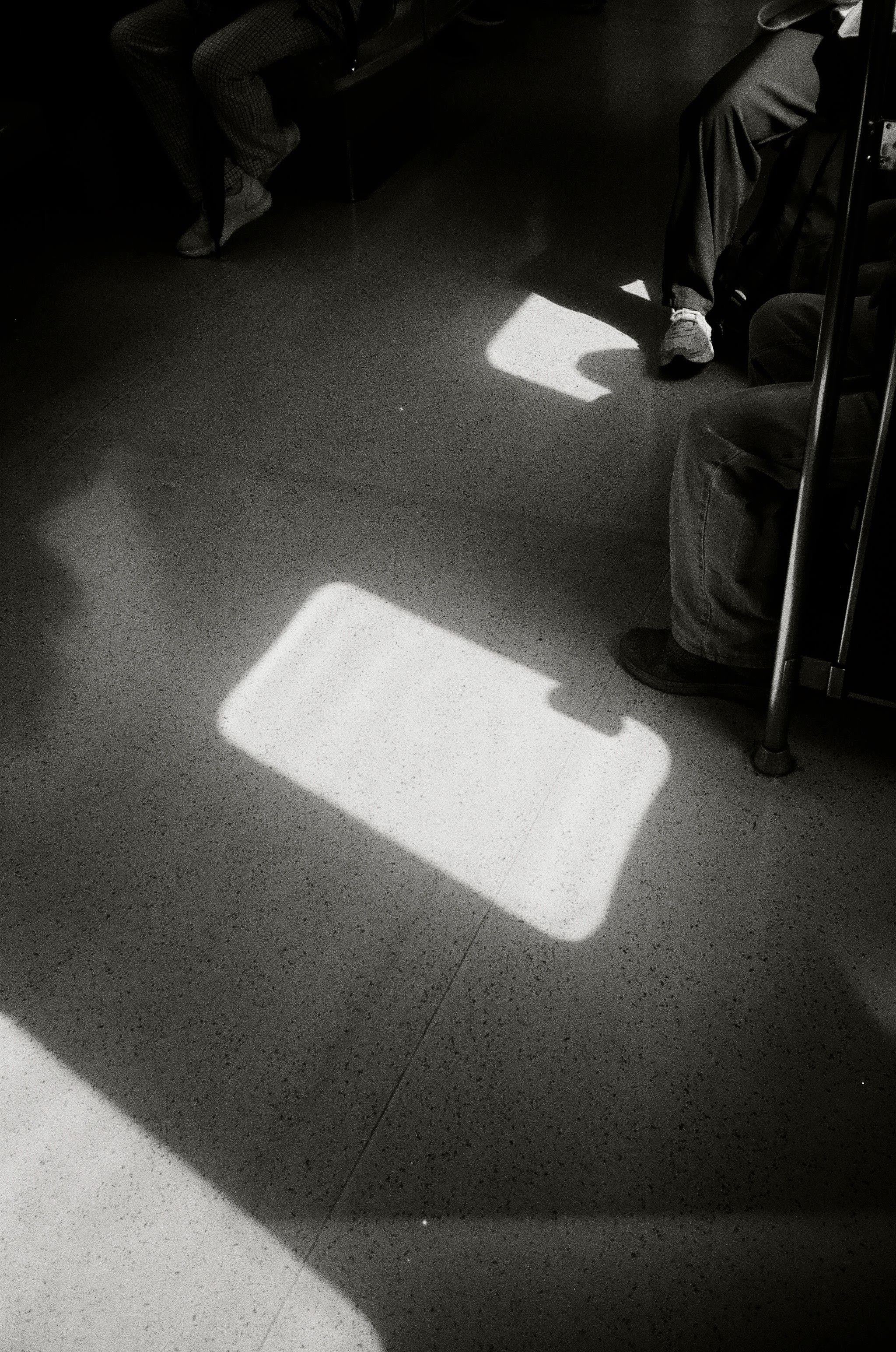 Black and white picture of the floor, capturing bright sunlight that is being cast through the window.
