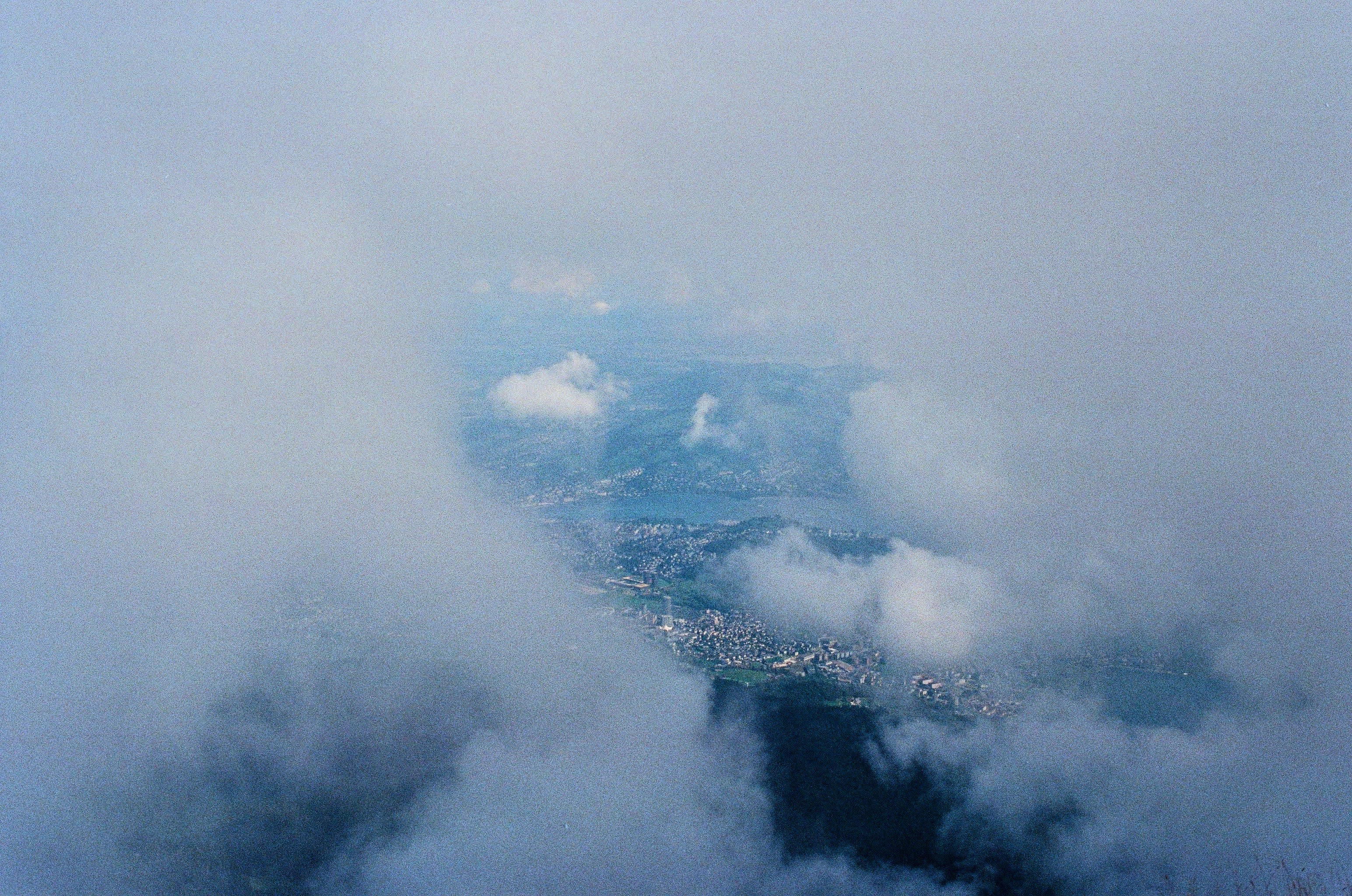 A view looking down on a city through gaps in thick clouds.