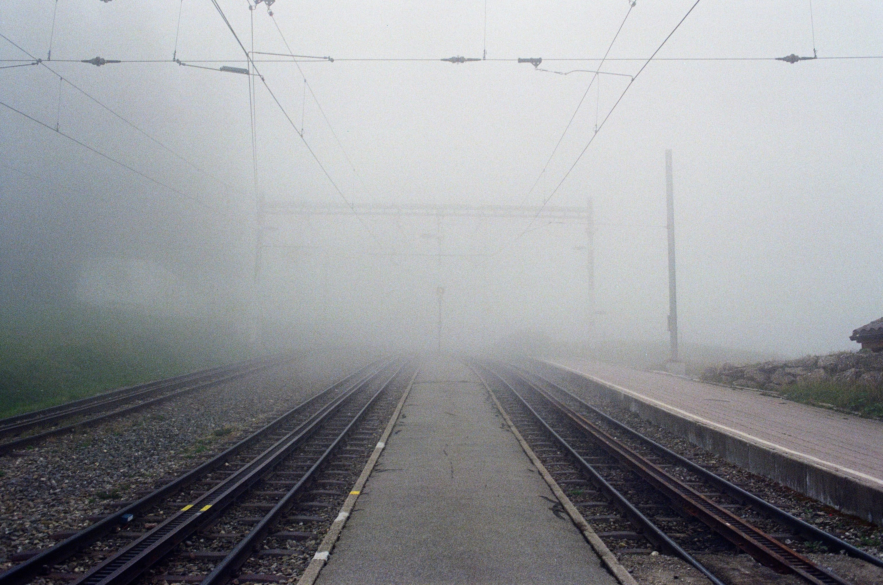 View of two railway tracks heading away from a platform into a very misty scene.