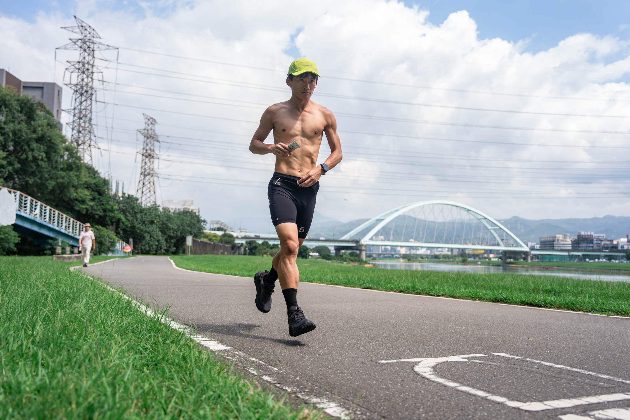 跑者穿著 FlipBelt 競速短褲於河濱跑步，手持補給包
