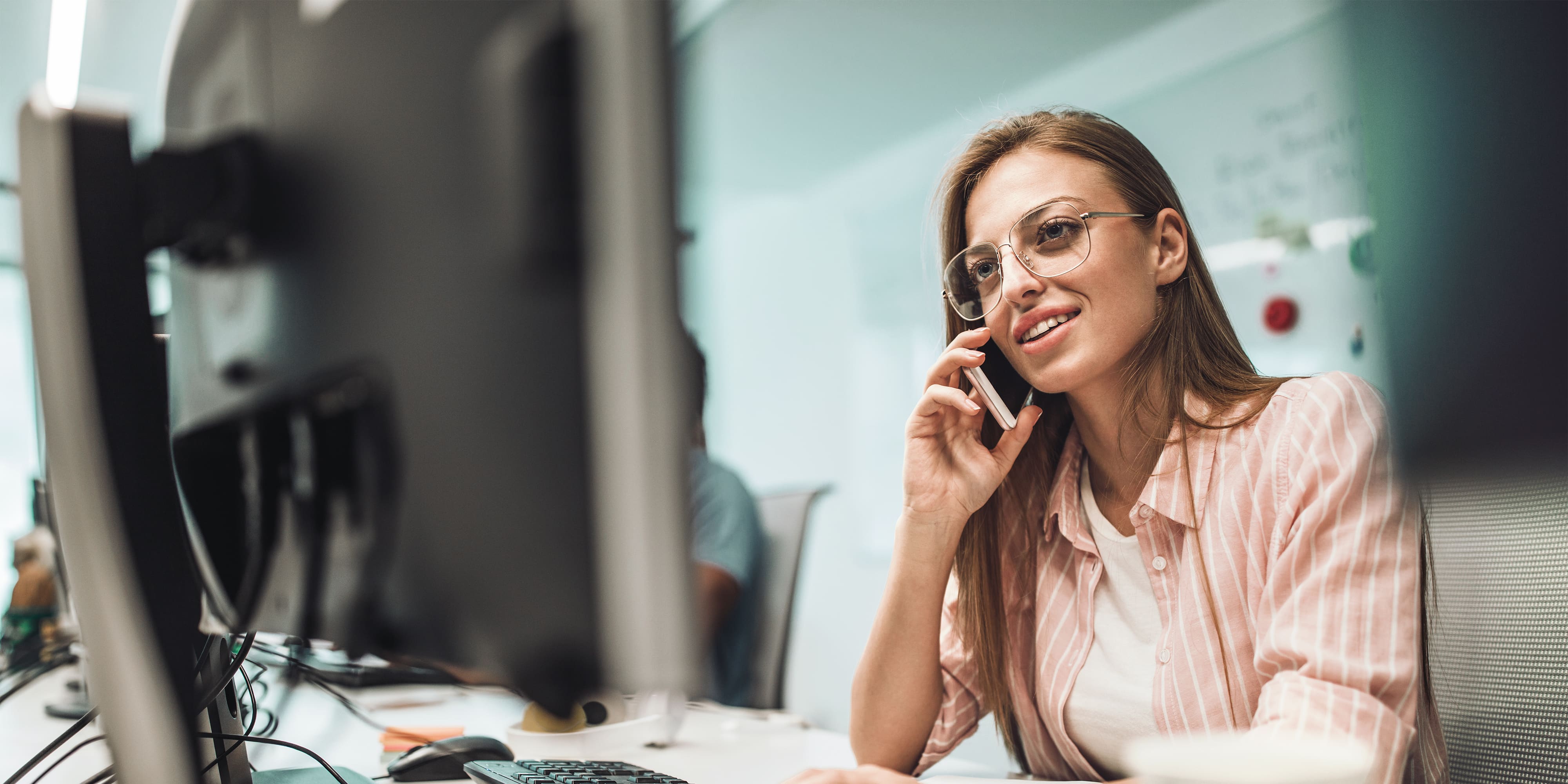 Glücklich weiblichen Programmierer telefonieren mit Handy während der Arbeit im Büro.