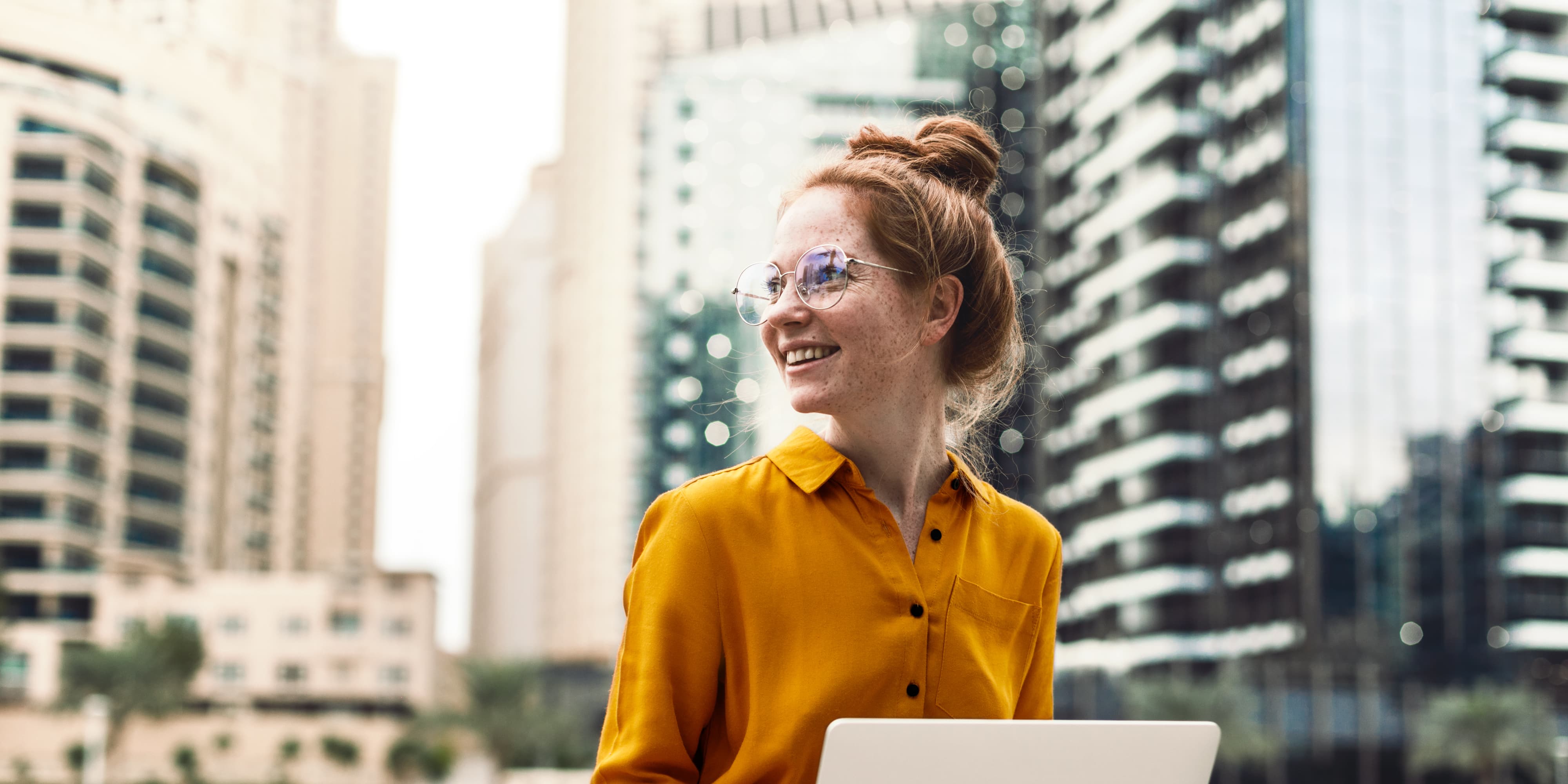 Junge Frau sitzt in Dubai Marina Arie und arbeiten auf Laptop. Studentischer oder freiberuflicher Lebensstil.