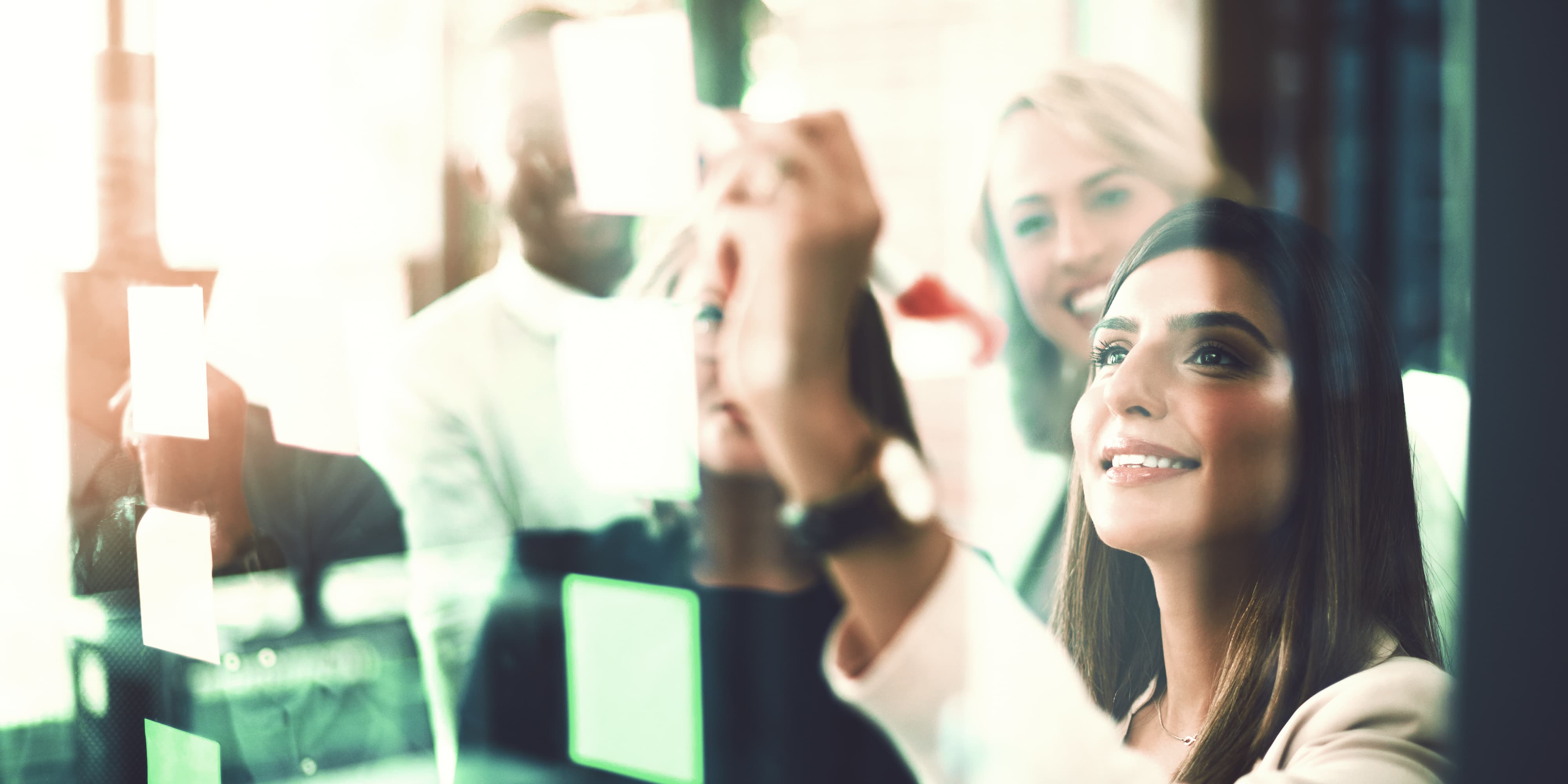 Team arbeitet an Glaswand im Büro