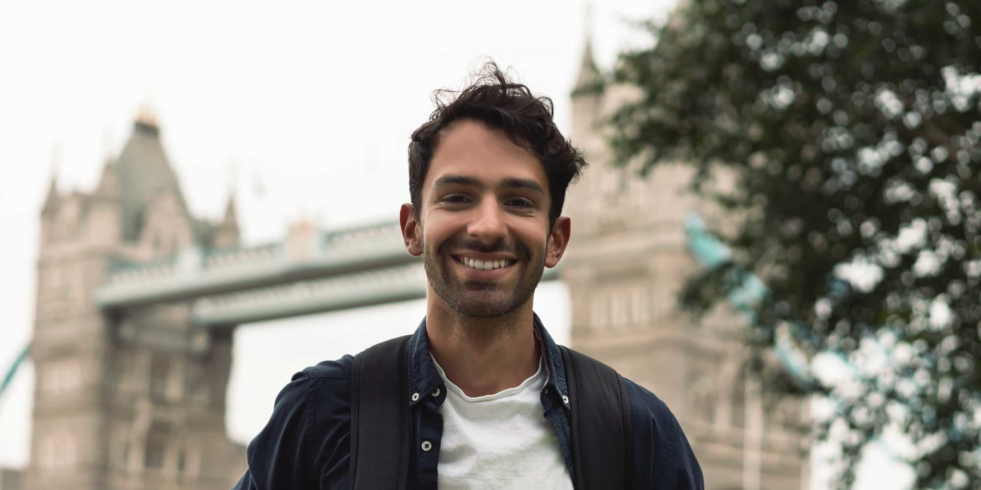 Junger Student mit Rucksack und Block vor der Tower Bridge in London