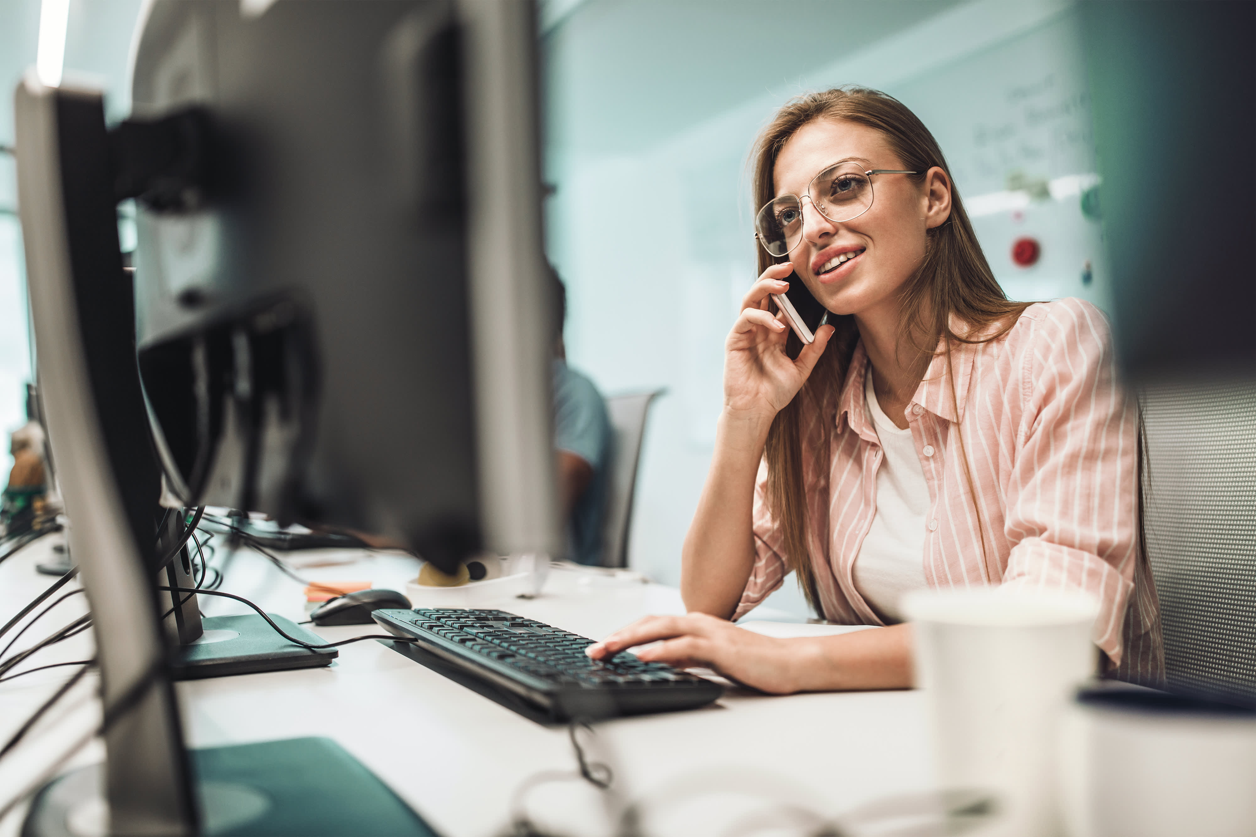 Glücklich weiblichen Programmierer telefonieren mit Handy während der Arbeit im Büro.