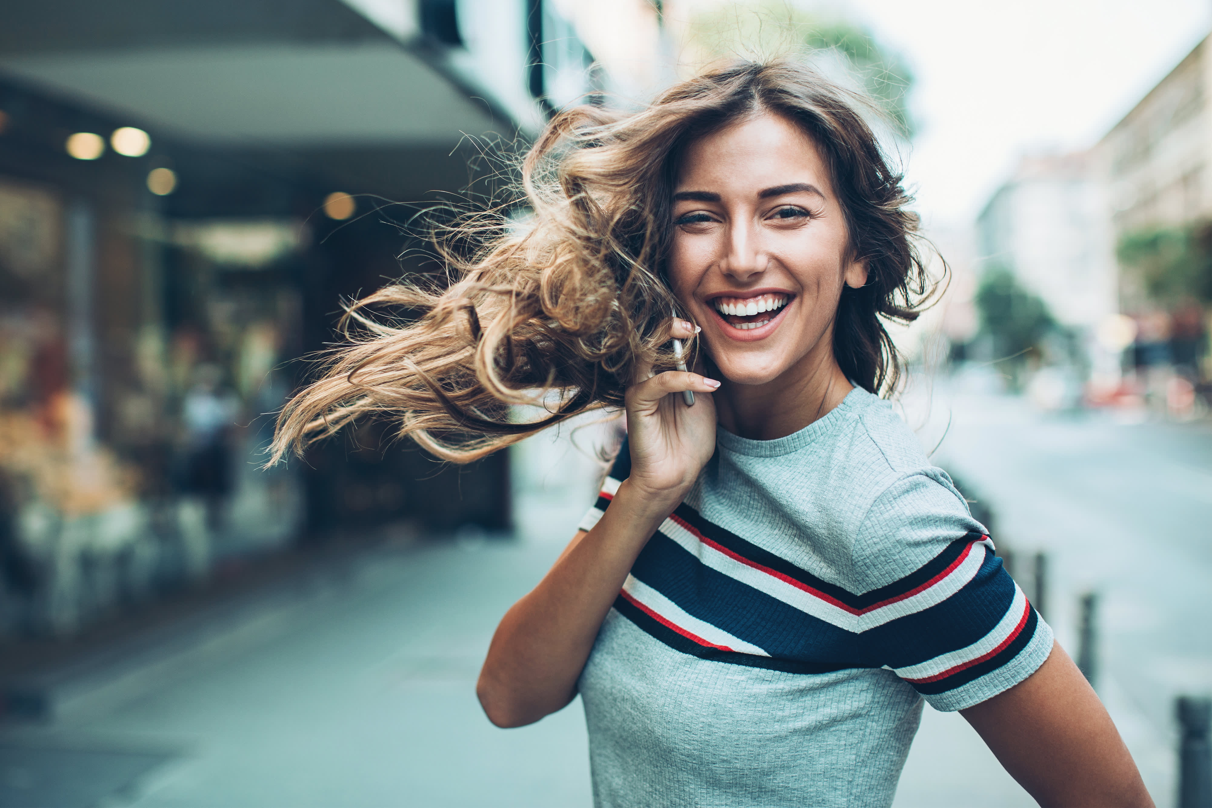 Junge Frau draußen auf der Straße telefoniert mit dem Smartphone
