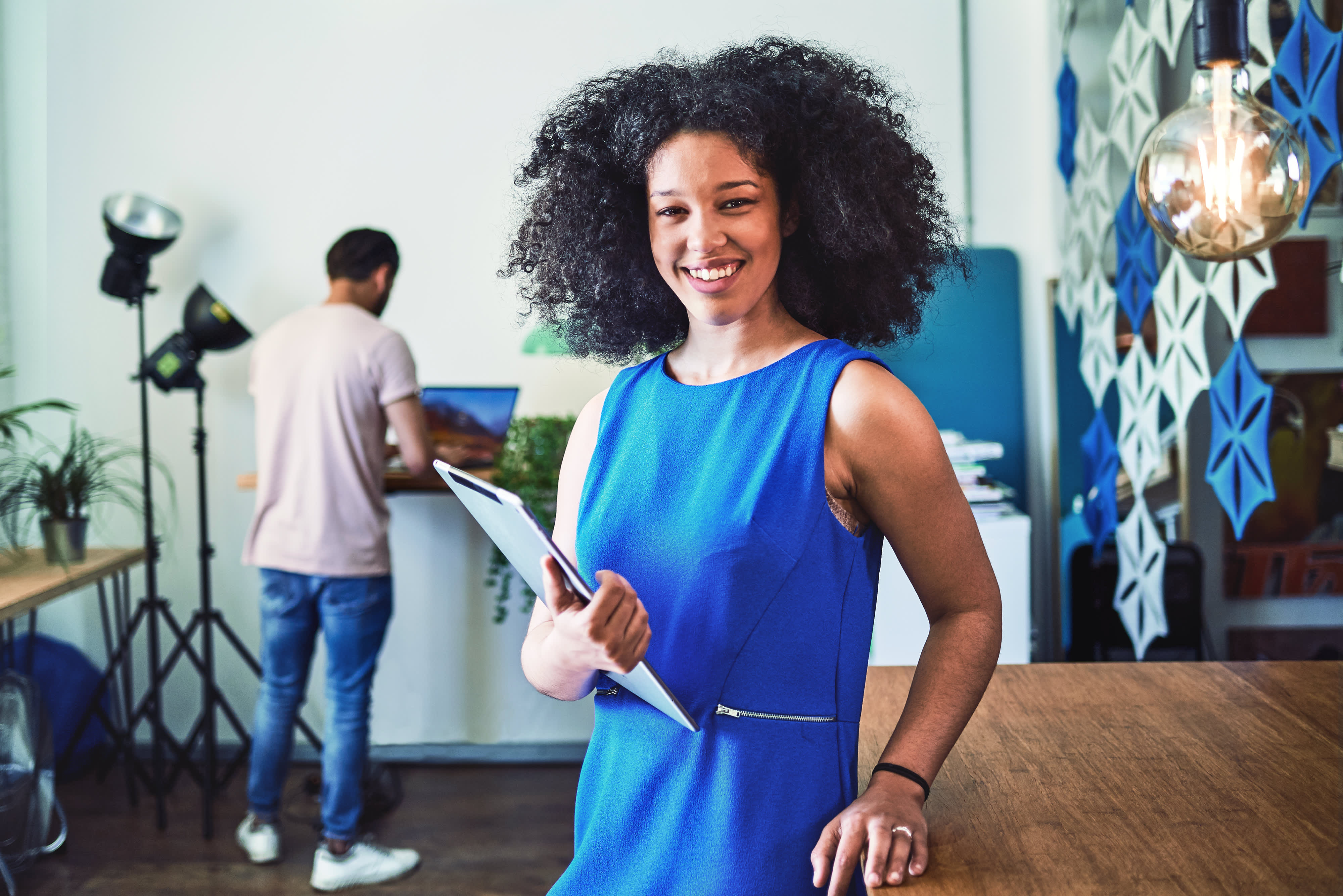Young mixed race female holding tablet computer looking to camera in modern sustainable office space