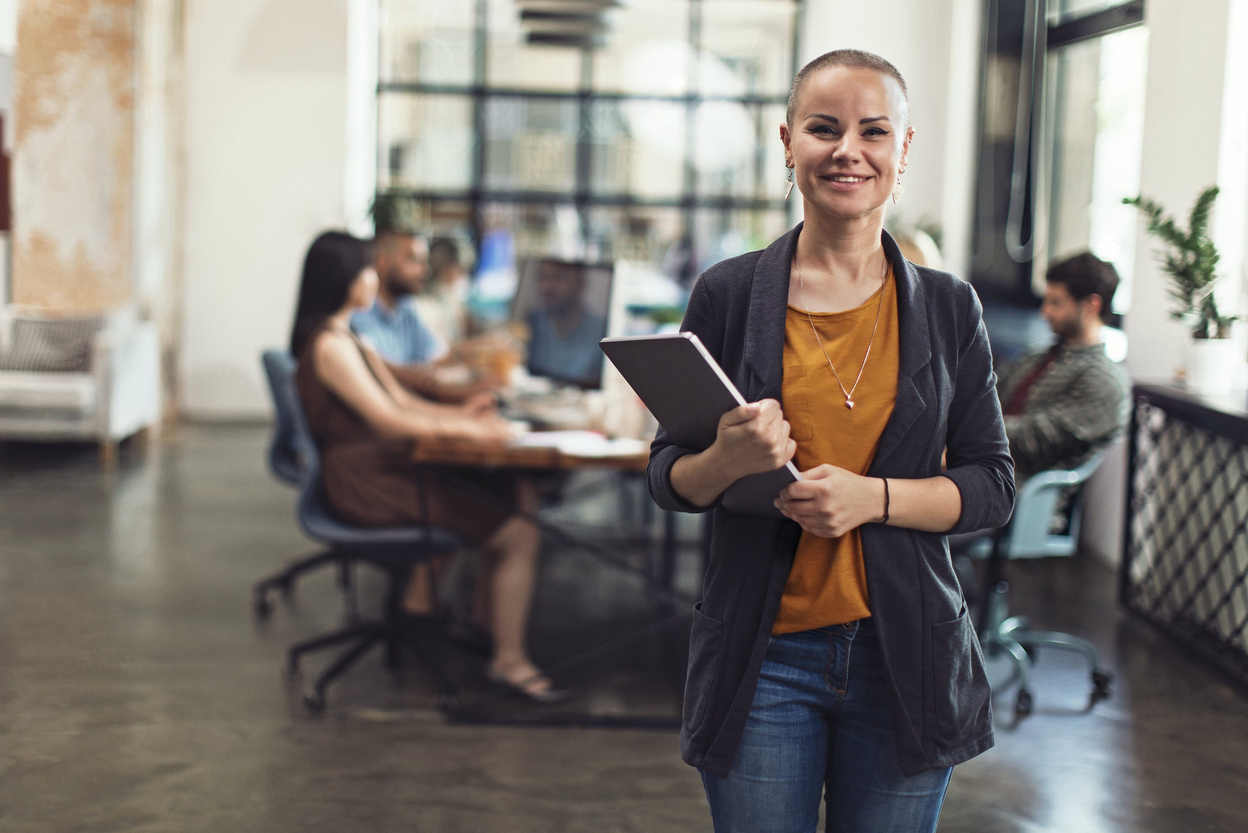 Profile shot of a smiling young woman standing in a co-working office space