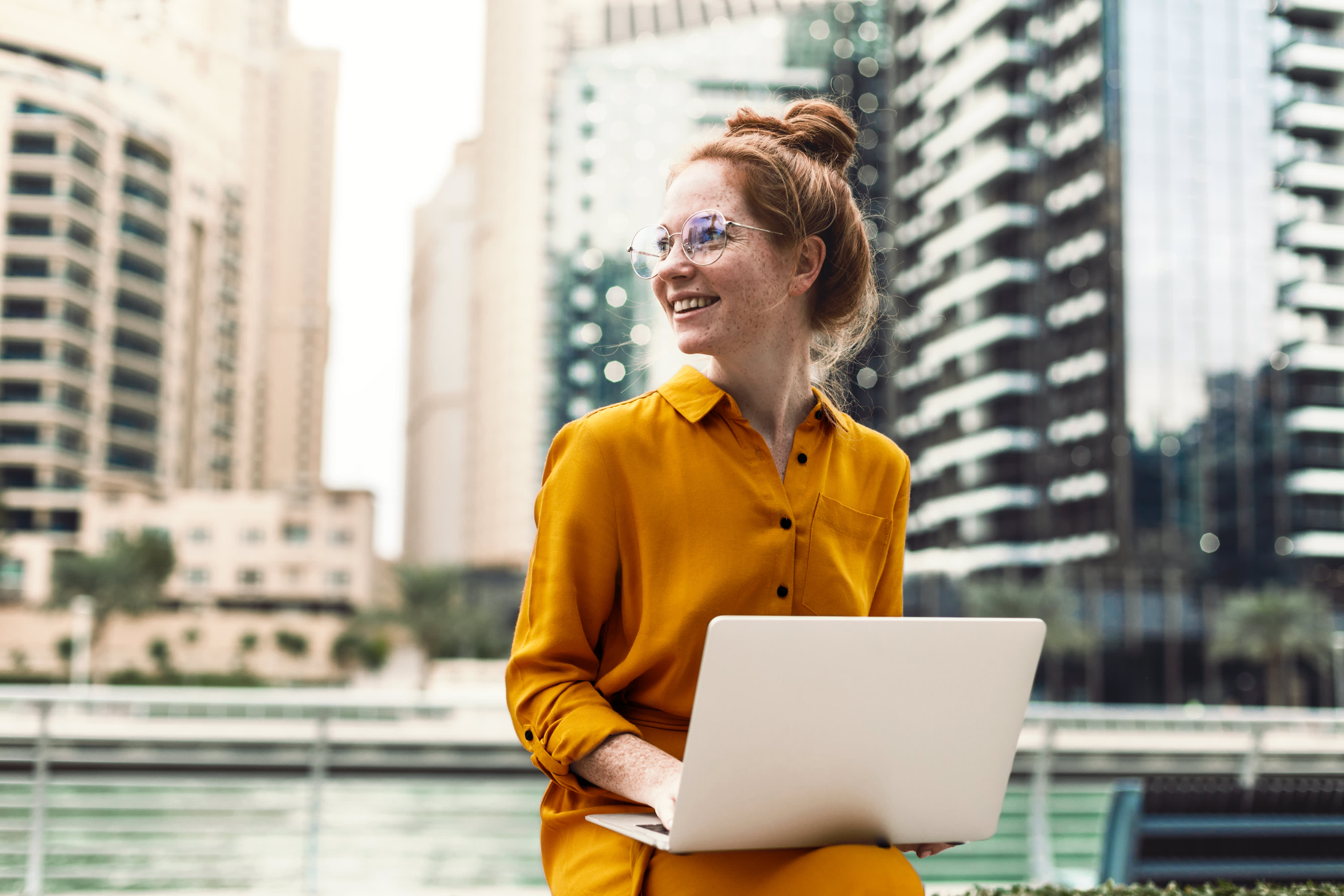 Junge Frau sitzt in Dubai Marina Arie und arbeiten auf Laptop. Studentischer oder freiberuflicher Lebensstil.