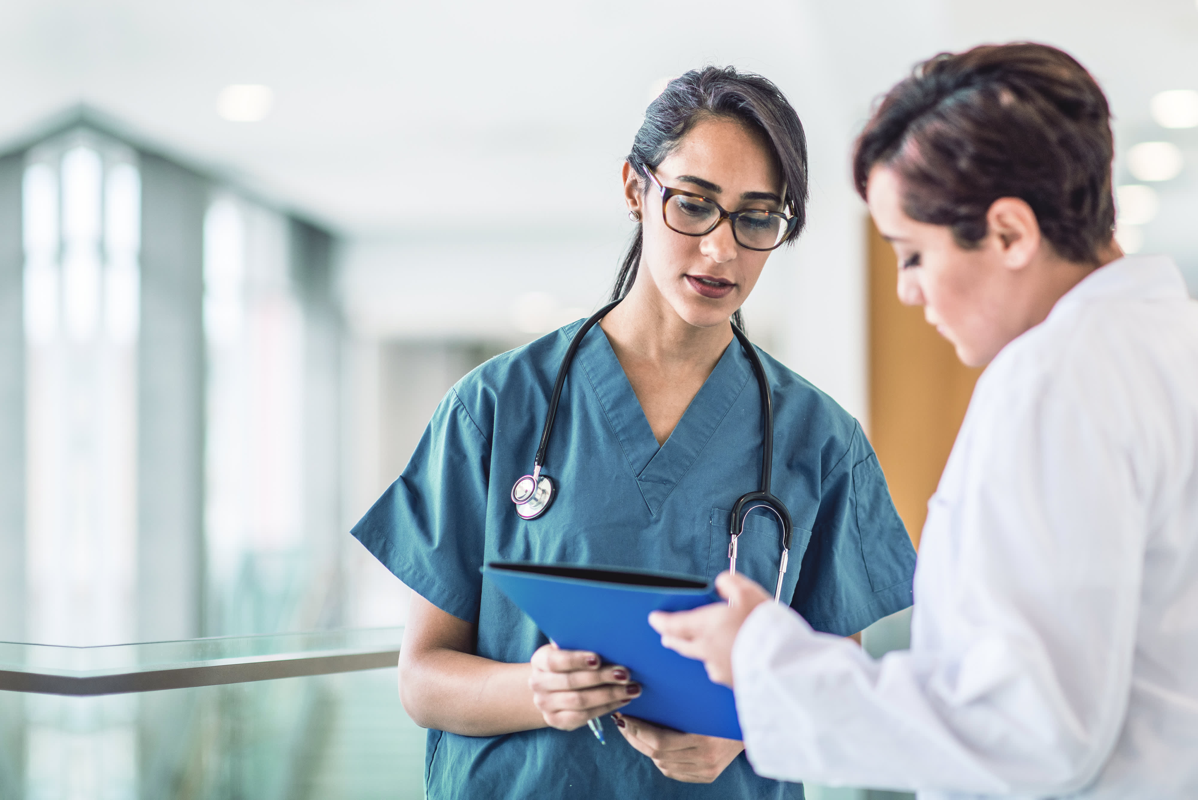 Ärztin und Krankenschwester diskutieren die Akte eines Patienten