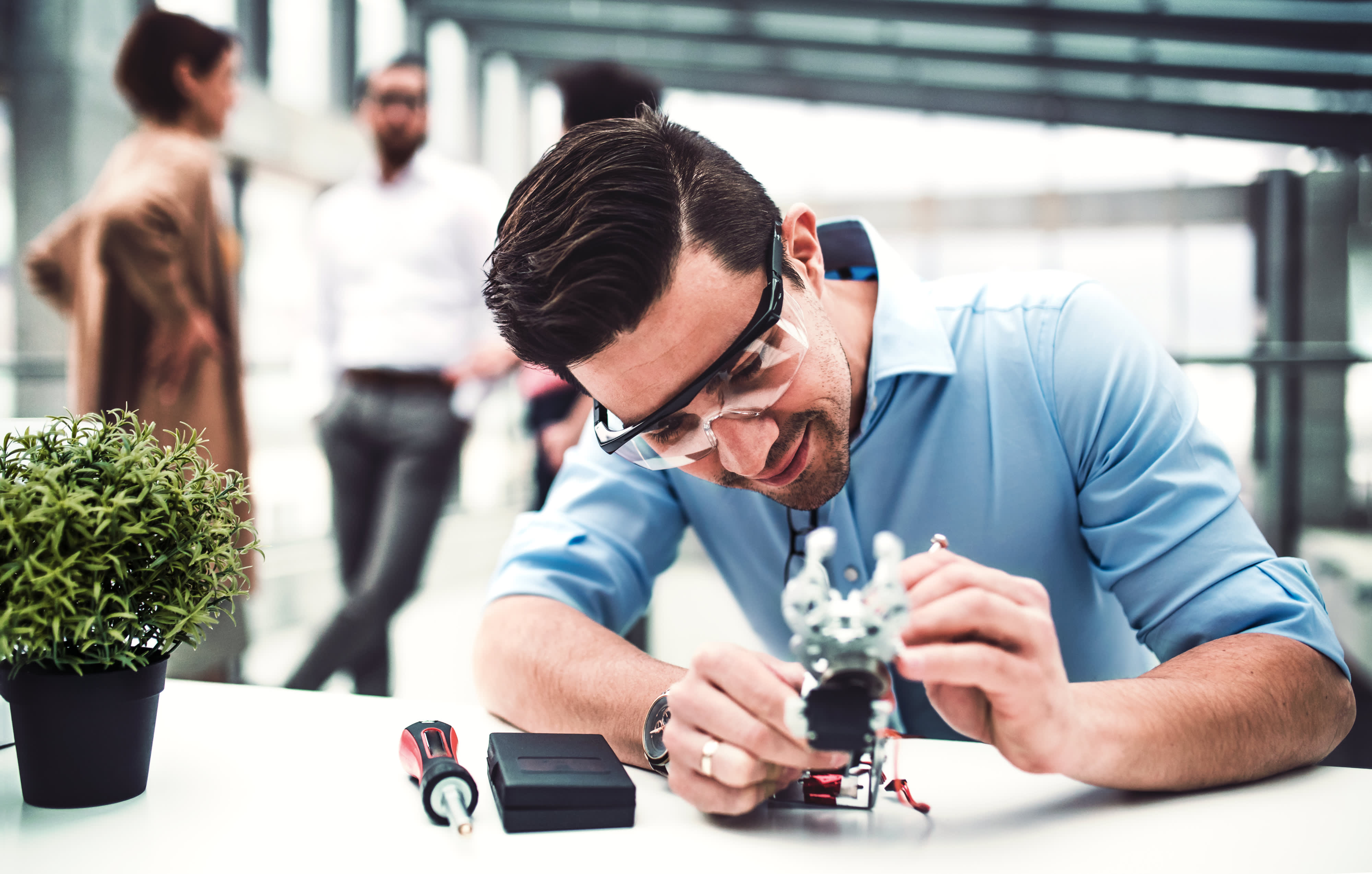 Ein junger Geschäftsmann oder Wissenschaftler mit robotischer Hand, die im Amt steht, arbeitet.