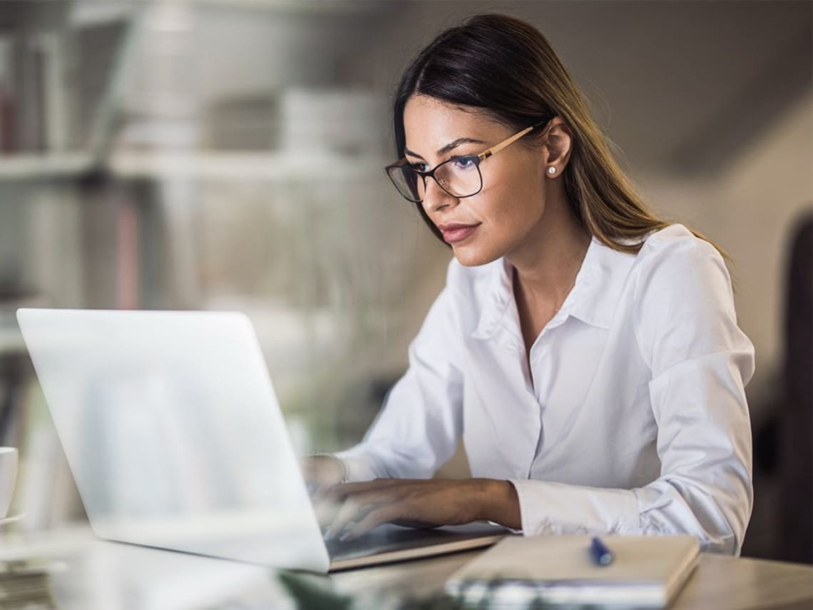 Studieninteressierte sitzt am Schreibtisch vor ihrem Laptop und informiert sich über ein duales Studium mit Fachabitur.