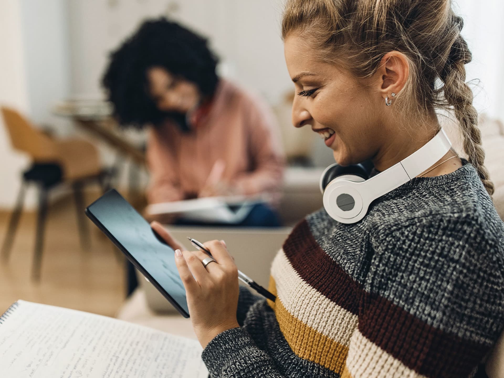 Studieninteressierte am Tablet und Notizen auf dem Schoß zum Motivationsschreiben eines dualen Studiums.