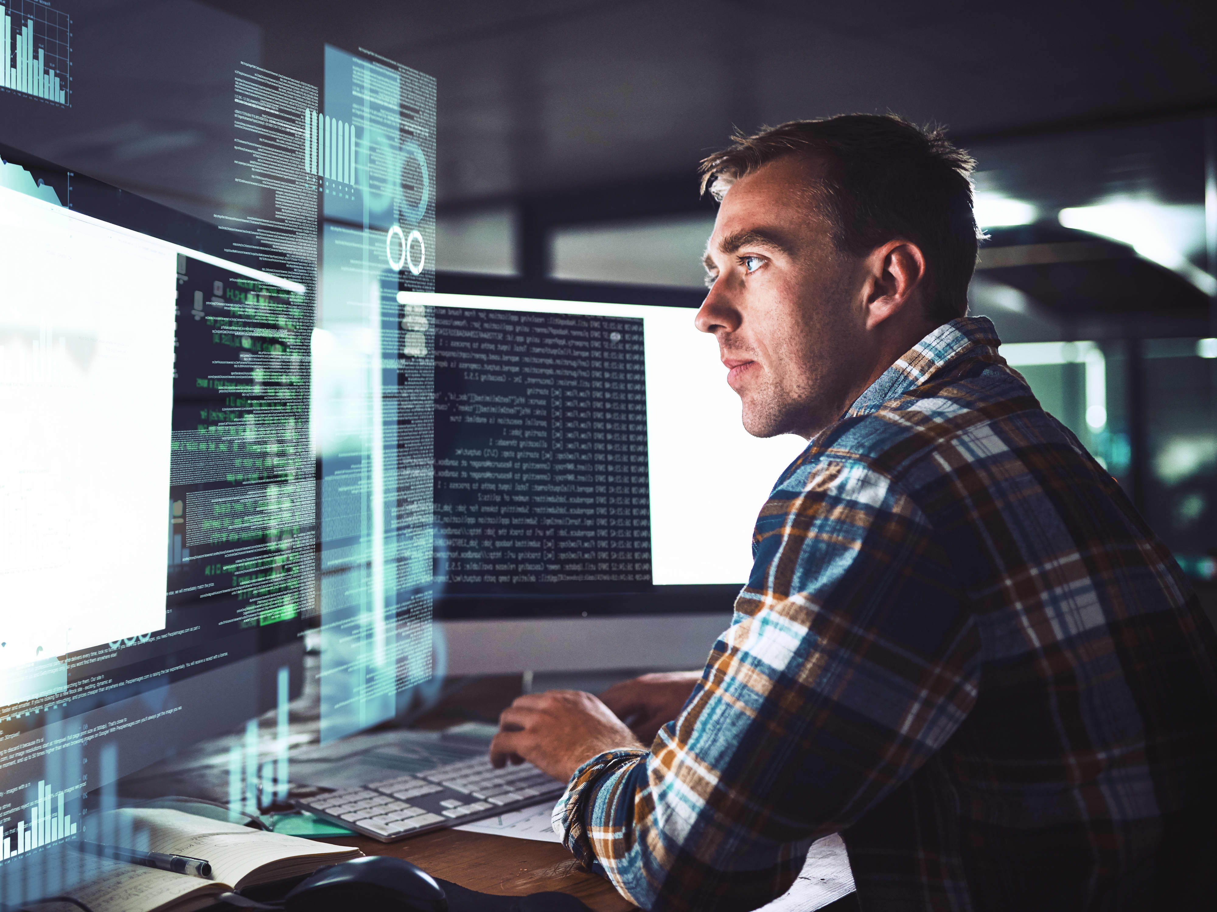 Titelbild der Infoseite "Duales Studium IT": Dualer Student sitzt vor seinem PC, wo Grafiken und Code angezeigt werden