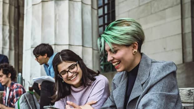 Zwei junge Frauen schauen gemeinsam auf ein Handy