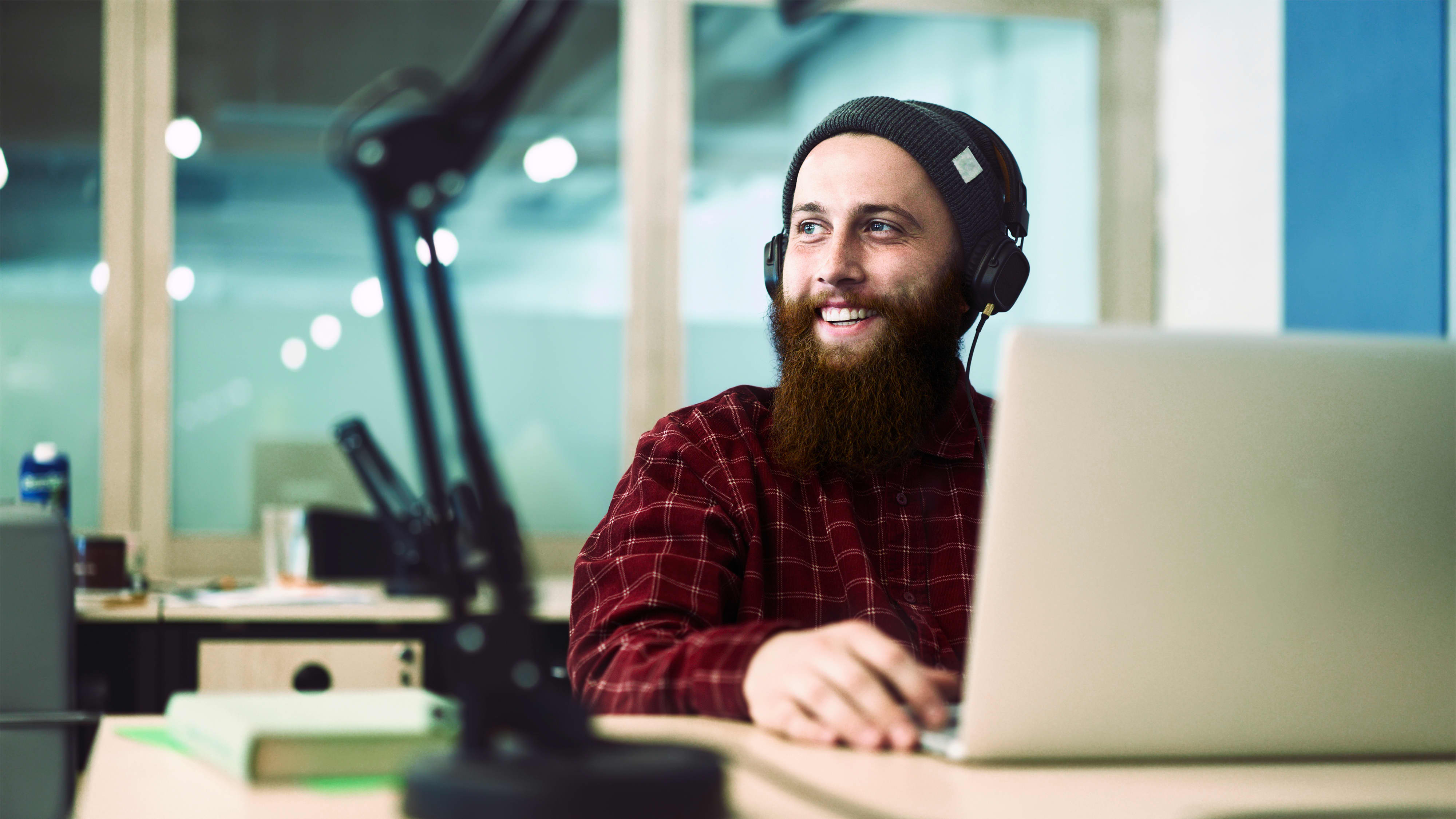 Titelbild für Infoseite “Bachelor UX Design”: Grafik-Designer mit Kopfhörern arbeitet am Laptop
